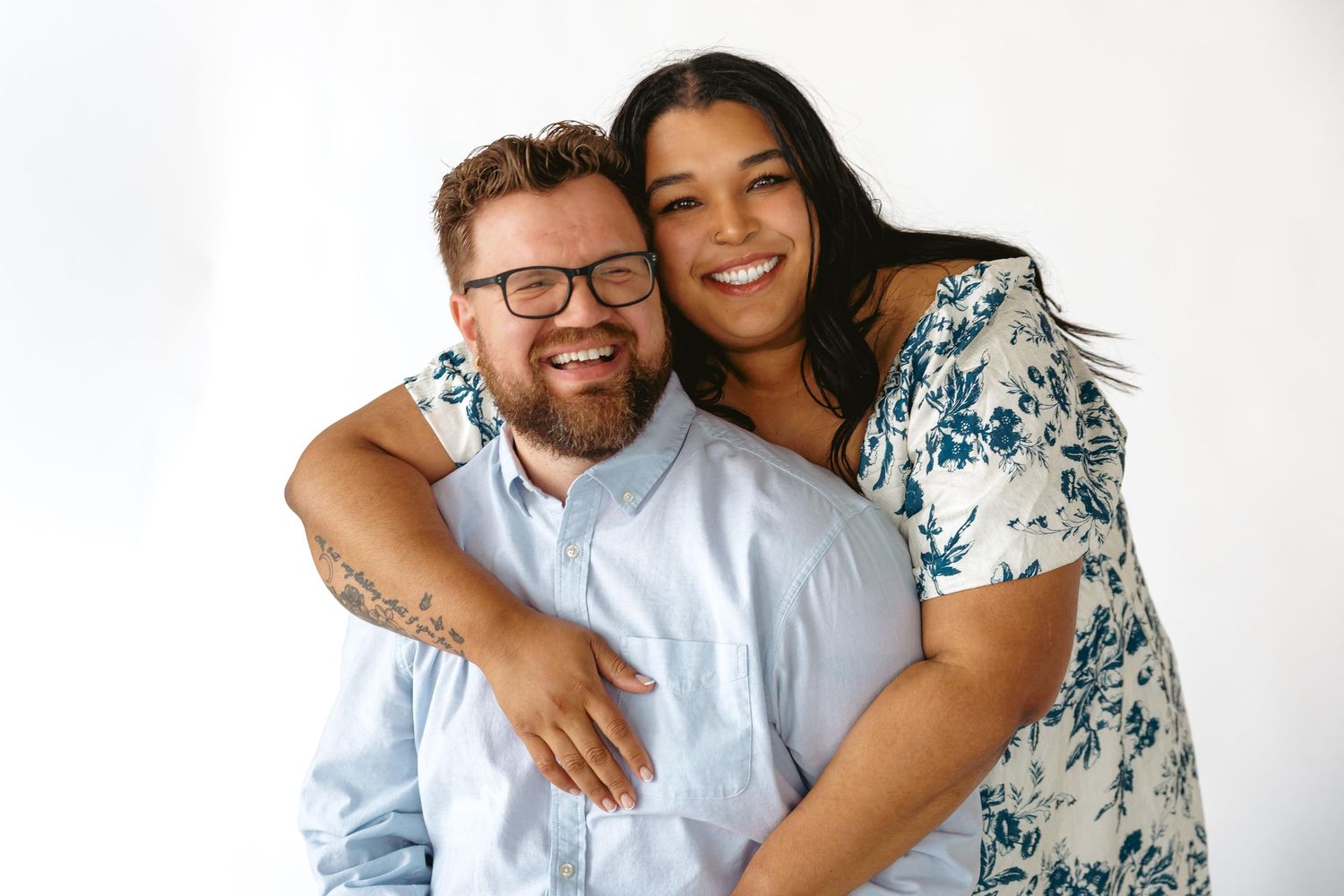Happy couple embracing and smiling together in a bright studio portrait setting.