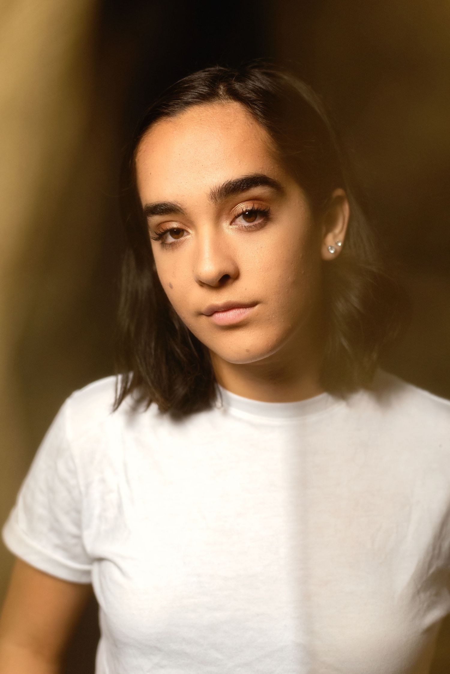 A person wearing a white t-shirt poses in a series of close-up portraits.
