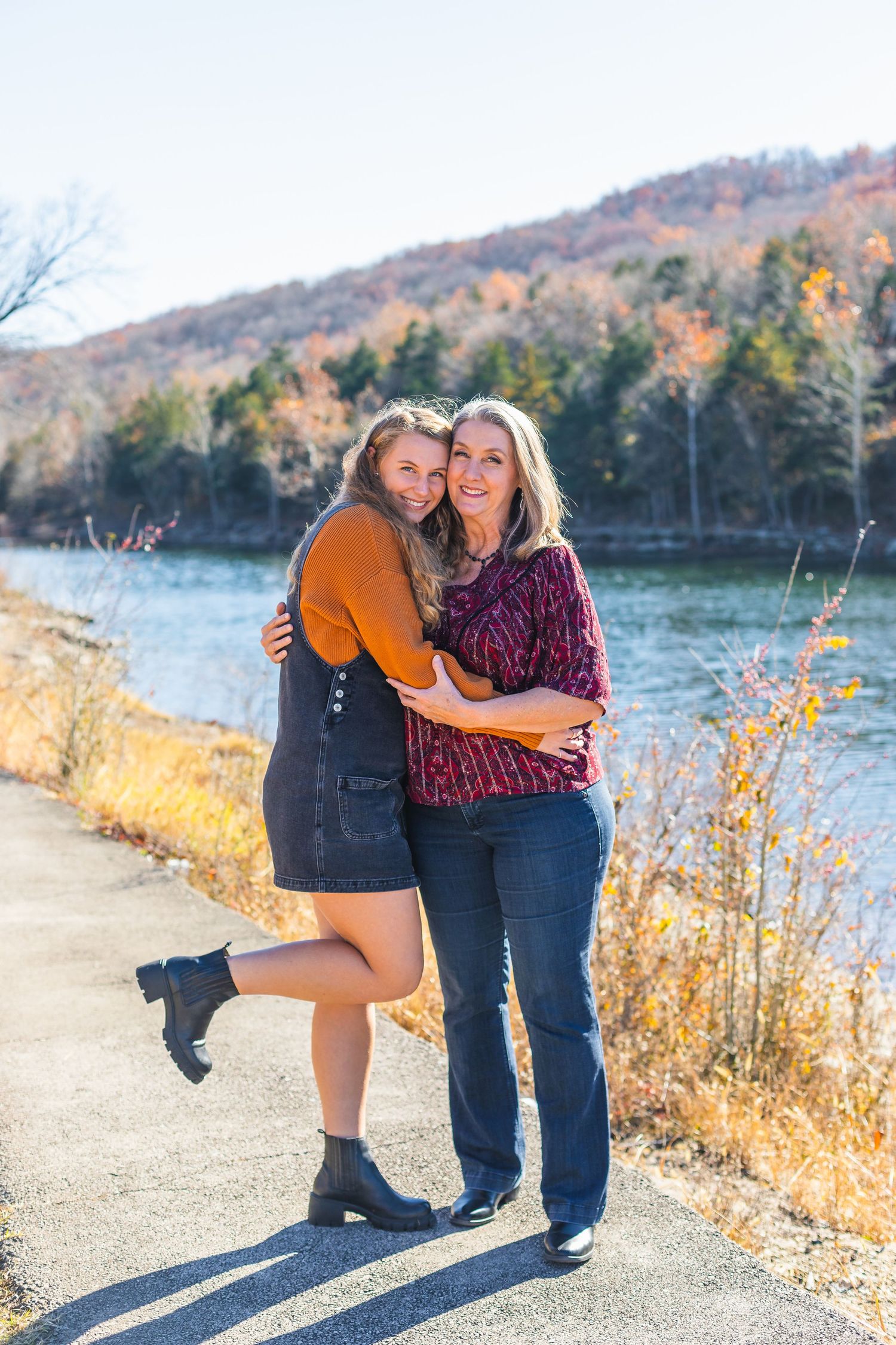 Autumn outdoor portrait by lake with fall foliage in background in Branson, Missouri.