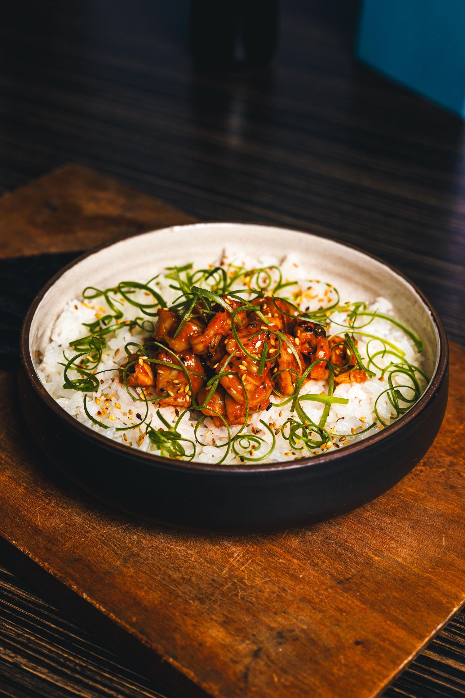 A dish featuring rice topped with colorful garnishes and spiraled green vegetables on a dark wooden surface at a restaurant in St. Louis.