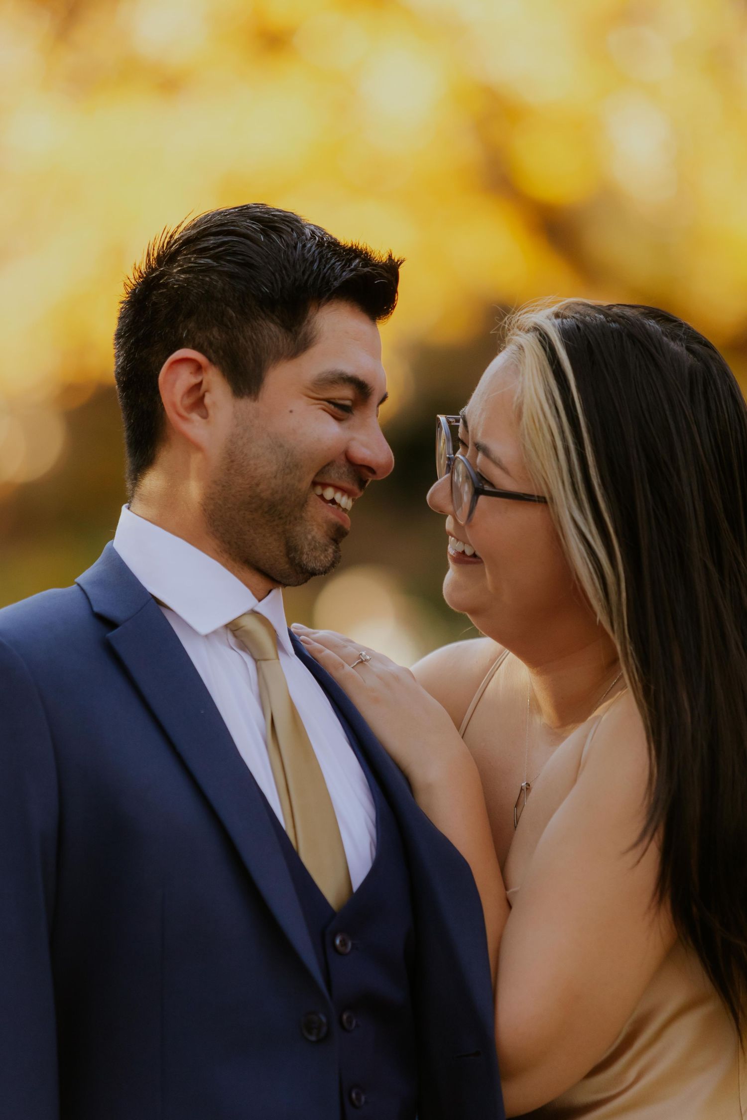 Close-up of engaged couple sharing joyful moment against blurred fall background at Lafayette Park in St. Louis.