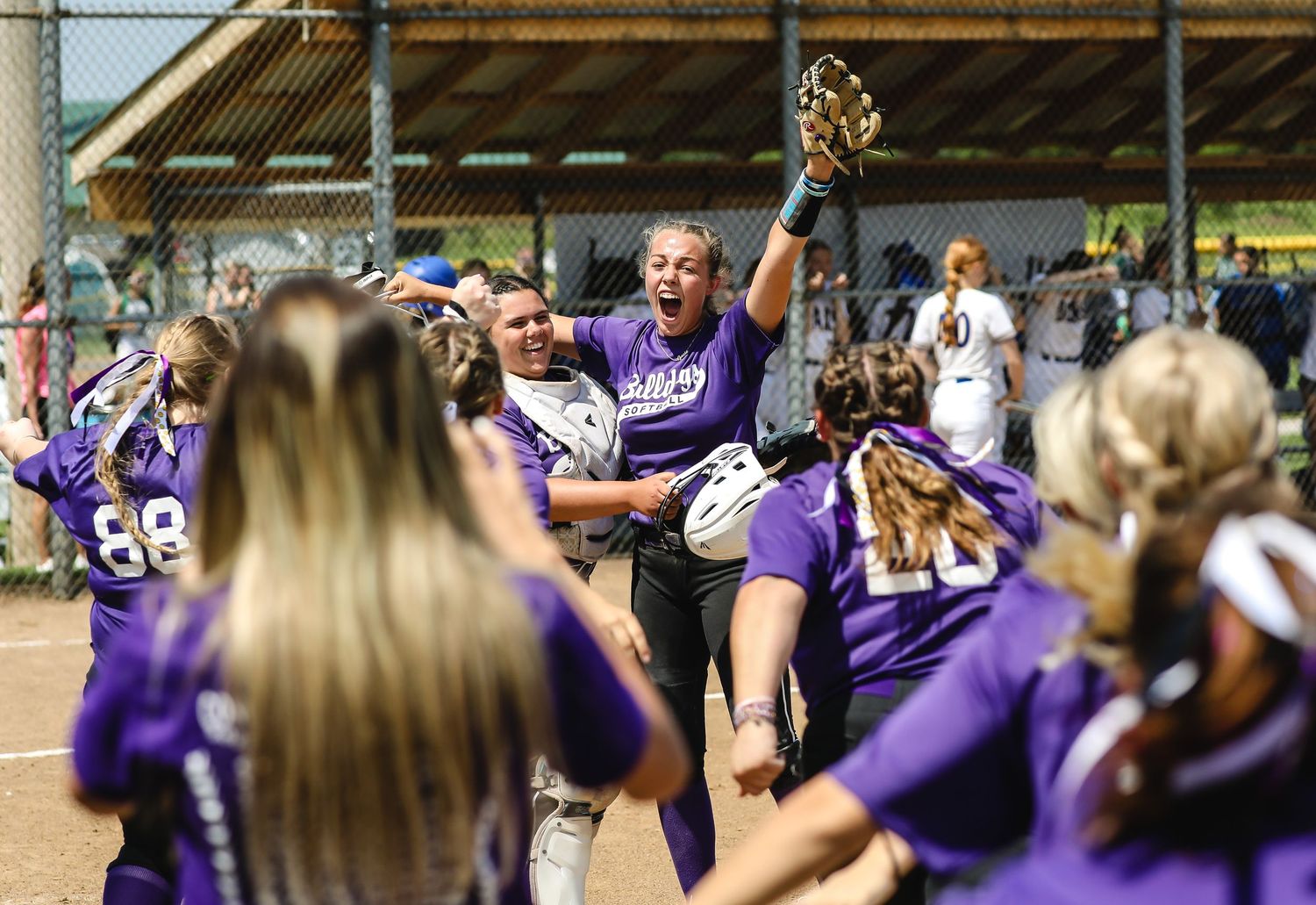 Softball team celebrating victory with player lifted in celebration.