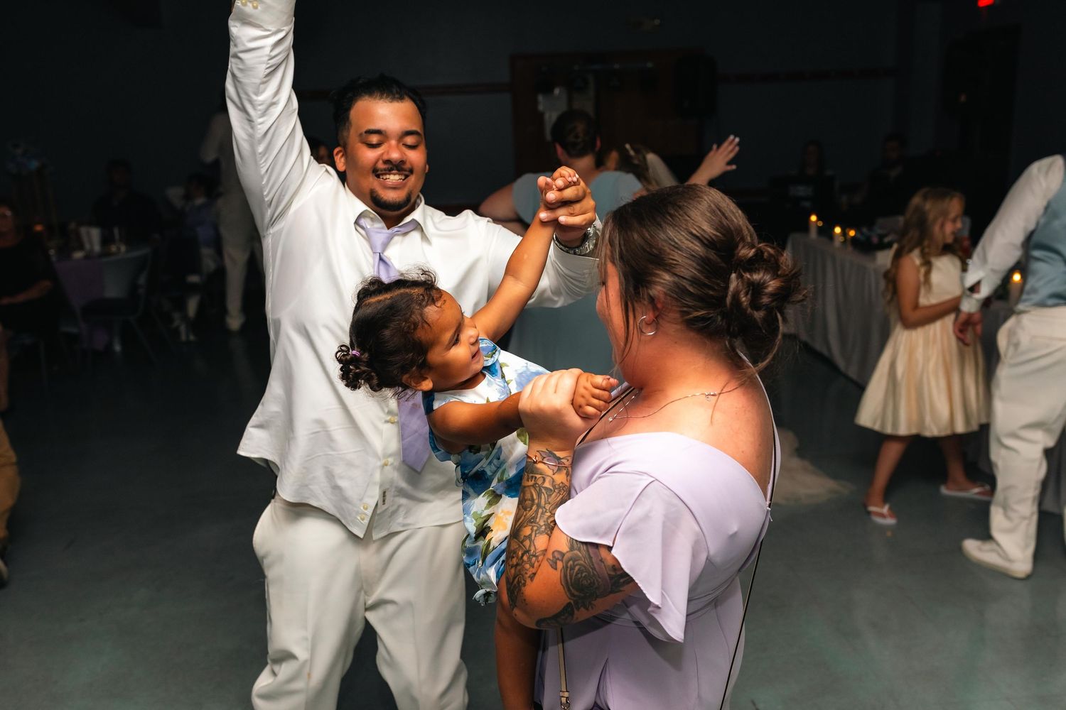 People dancing and celebrating at a wedding reception in formal attire.