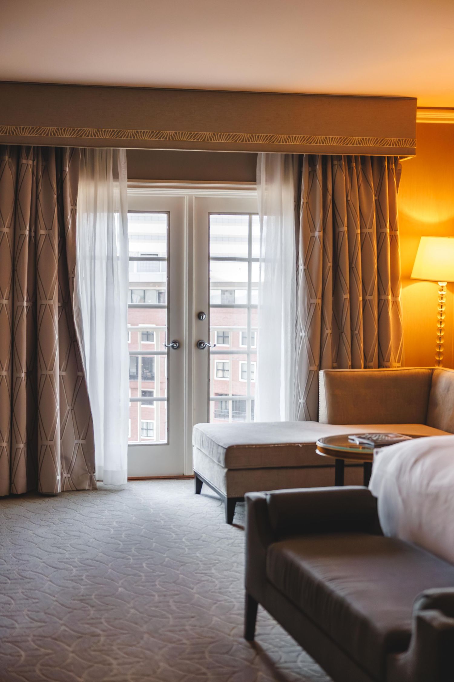 A modern hotel room interior with soft lighting, gray curtains, and a comfortable bed by the window.