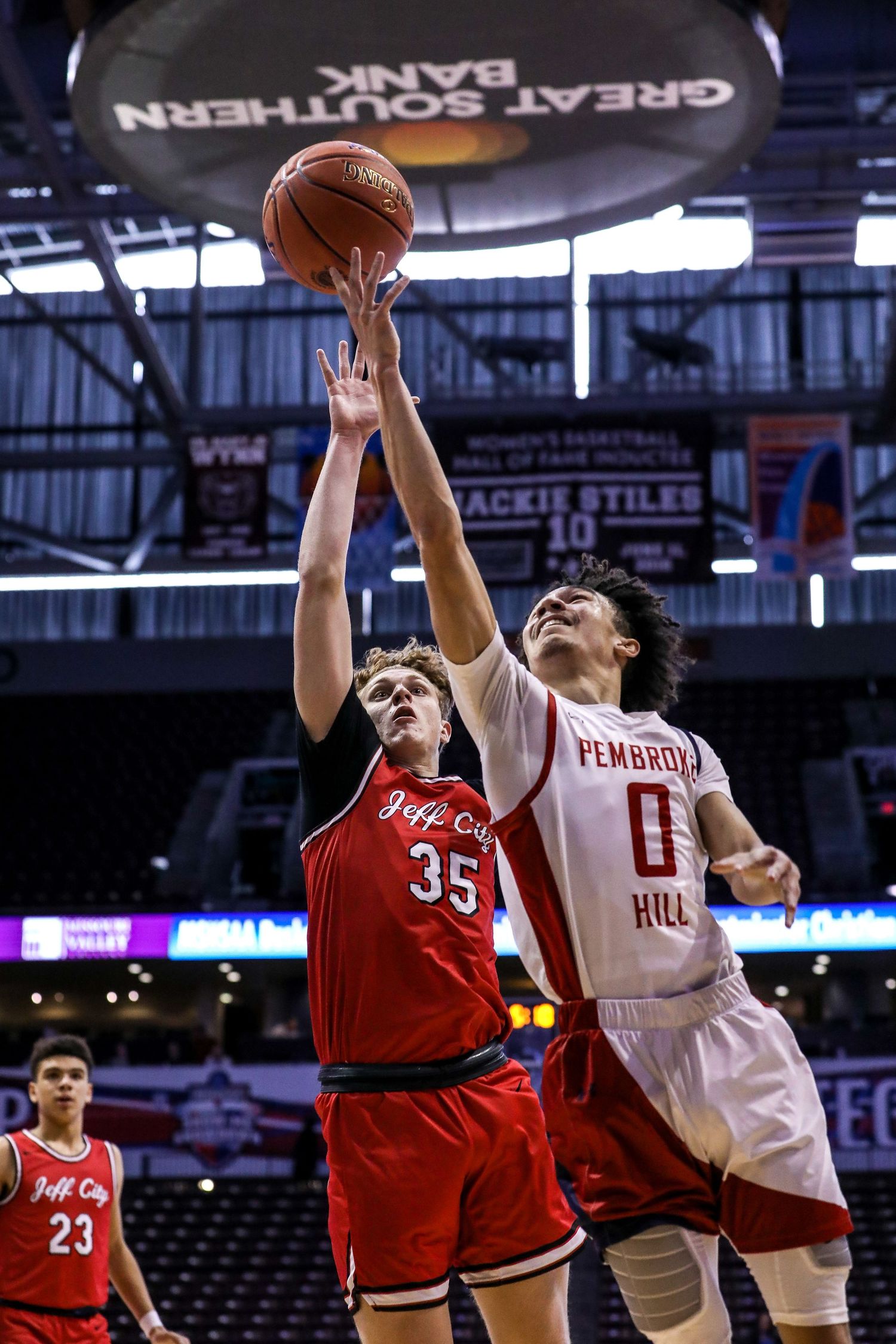 Basketball players jumping for rebound during intense game action.