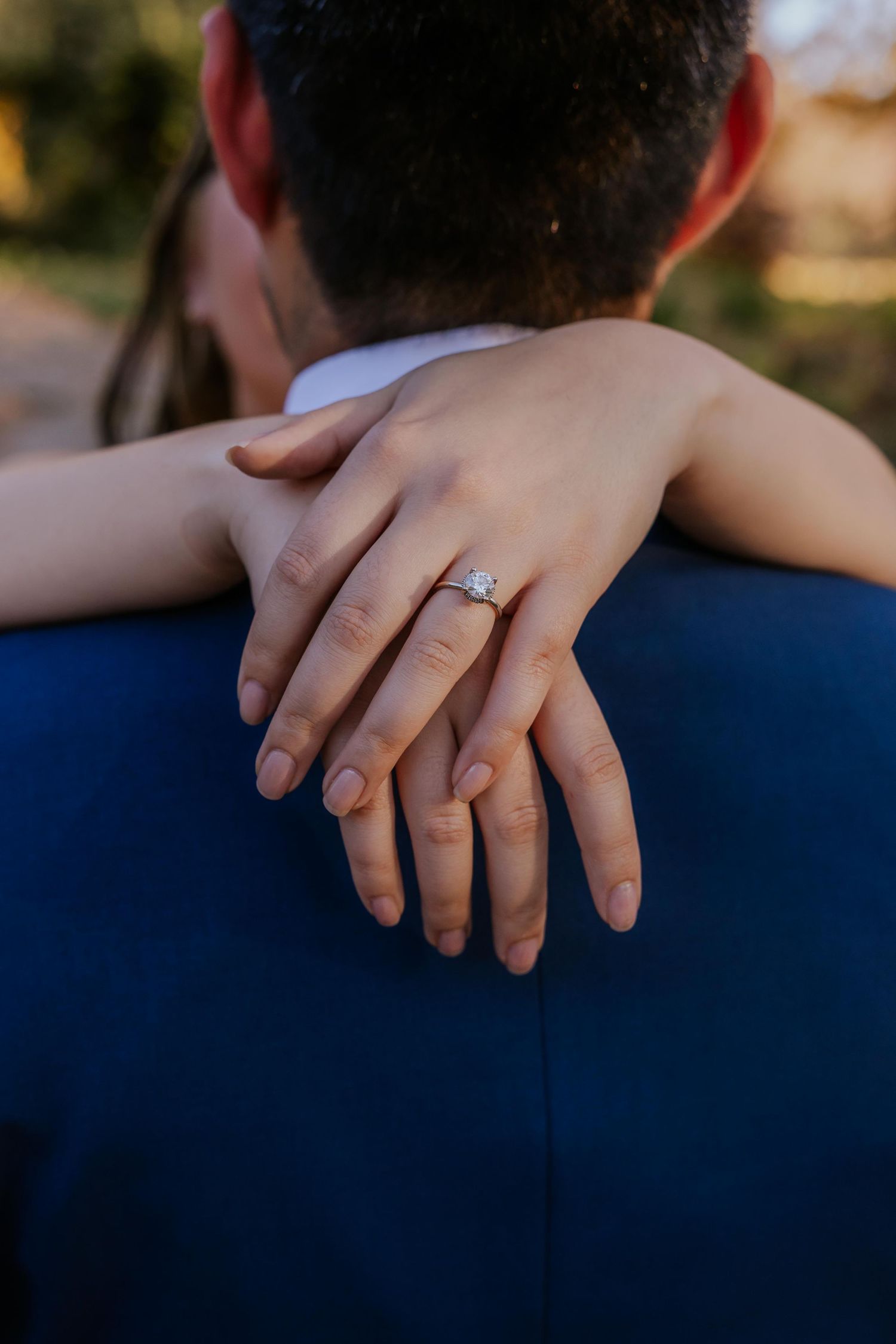 Close-up of hands with wedding rings against a navy blue suit jacket at Lafayette Park in St. Louis.
