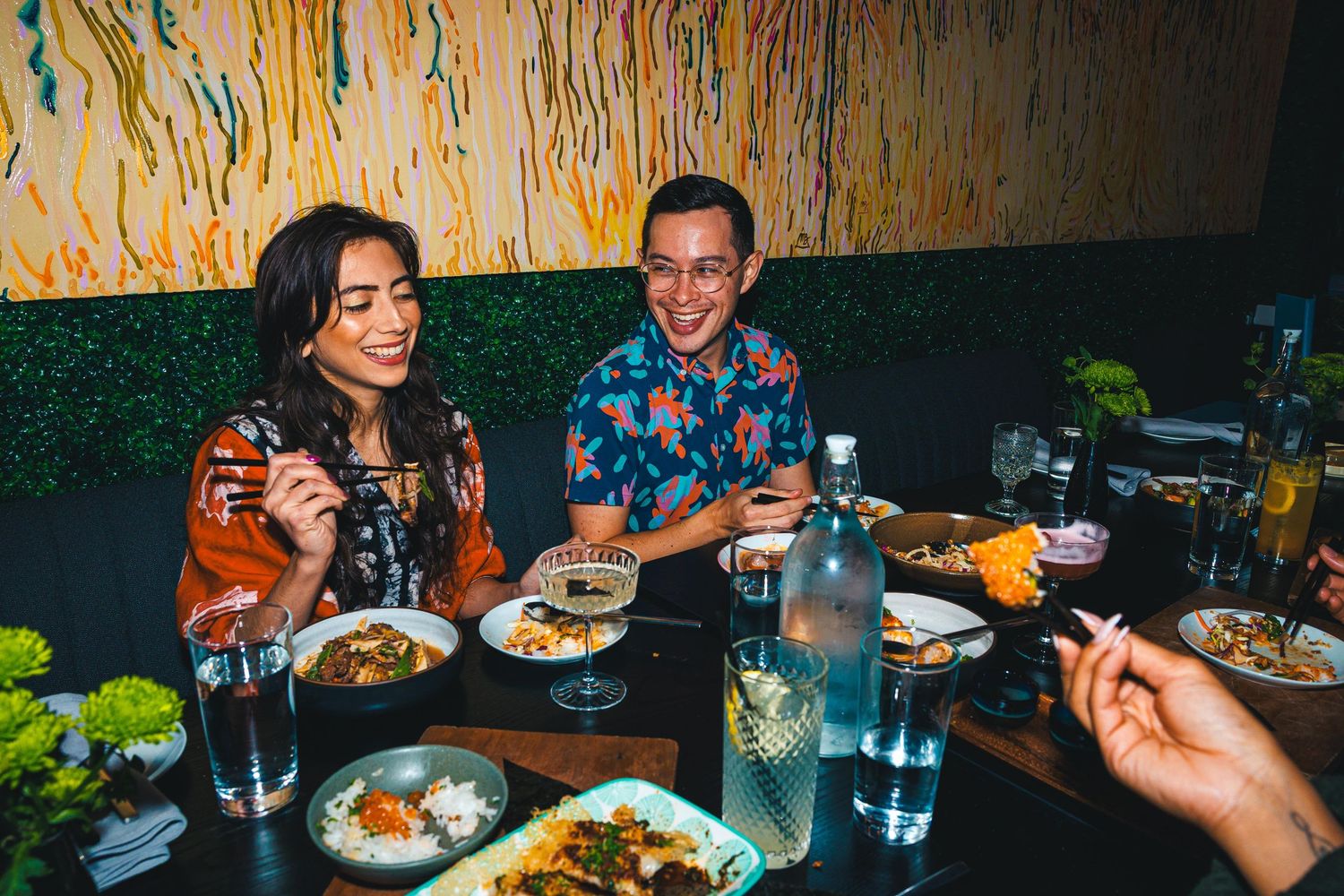 Diners enjoying a casual meal together at a restaurant with colorful wall art.