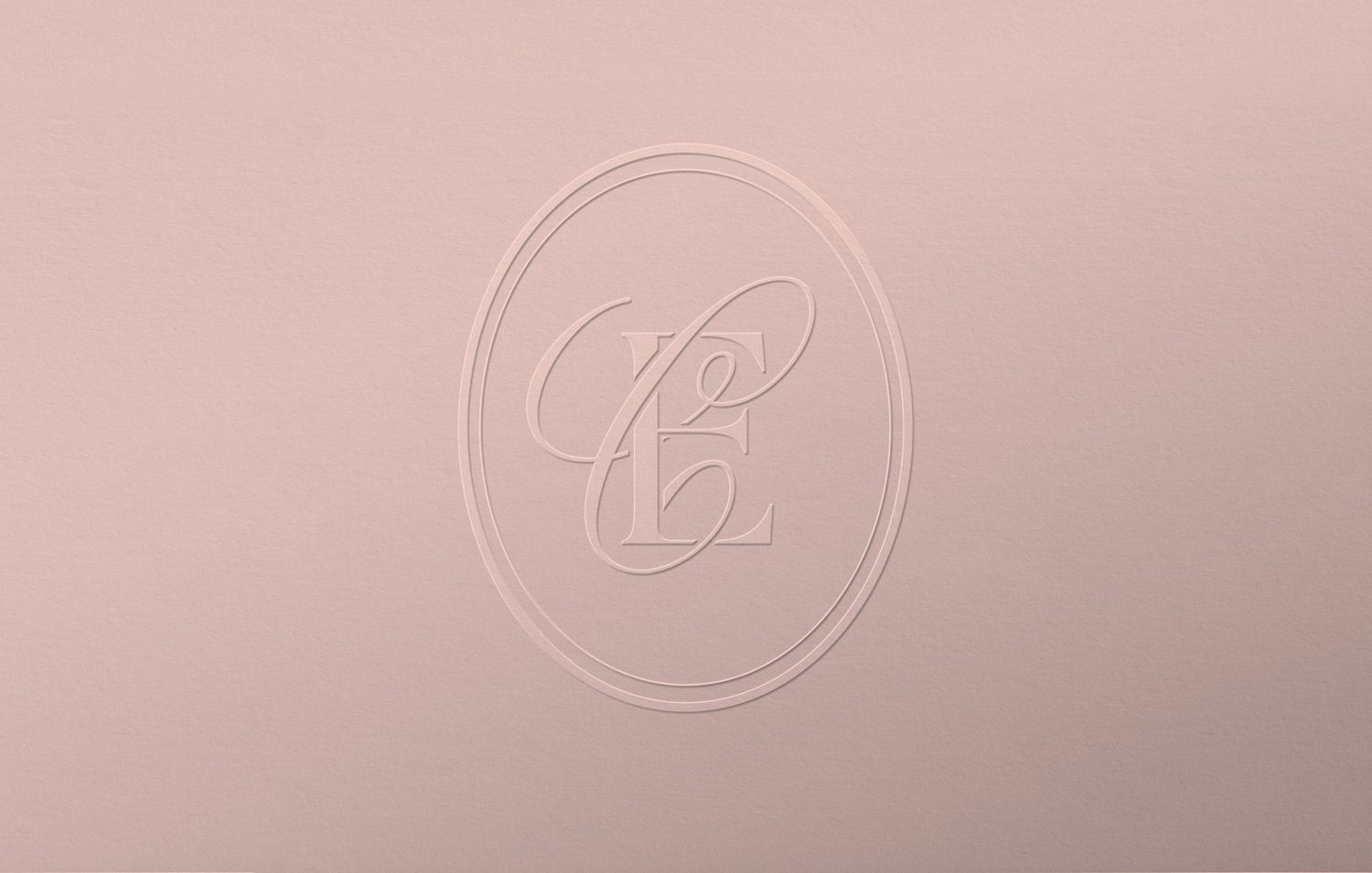 Elegant embossed monogram logo with intertwined letters on a soft blush pink background.