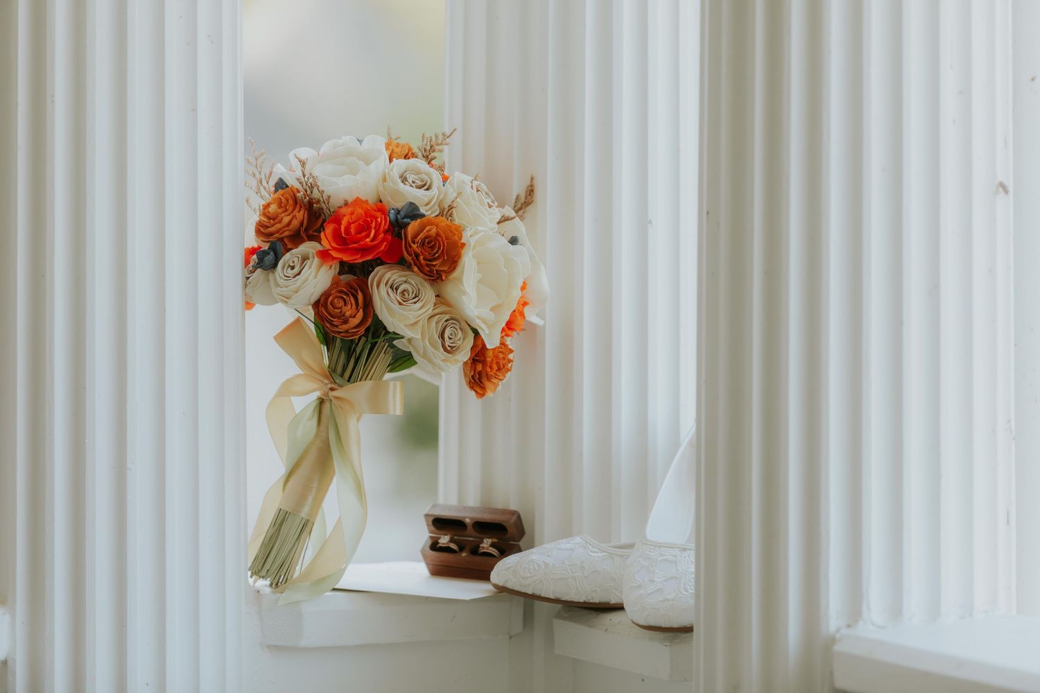 Orange and pink floral arrangements displayed against white vertical wall panels at wedding in St. Charles.