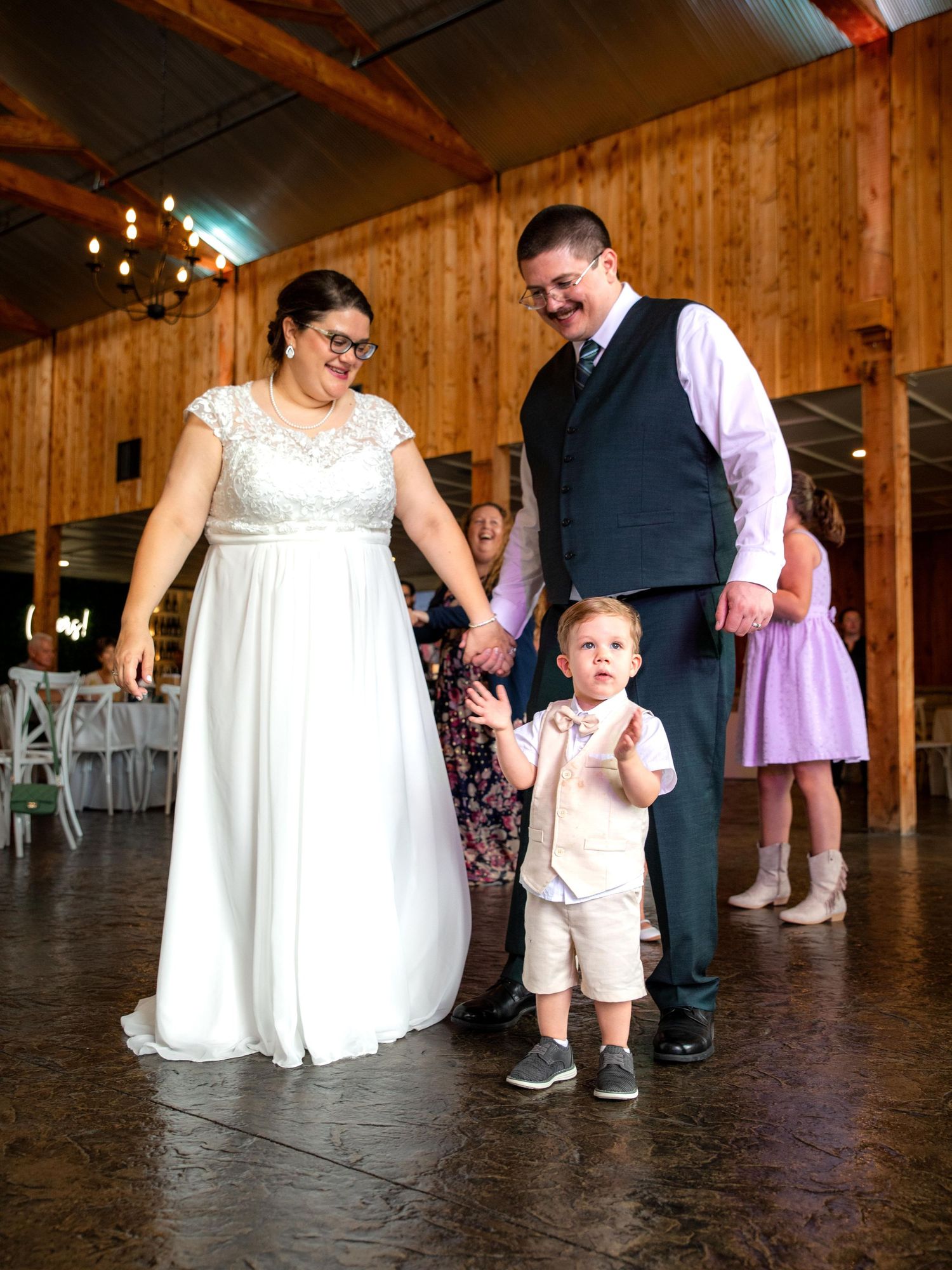Wedding guests dancing together on a rustic wooden dance floor in St. Charles, Missouri.