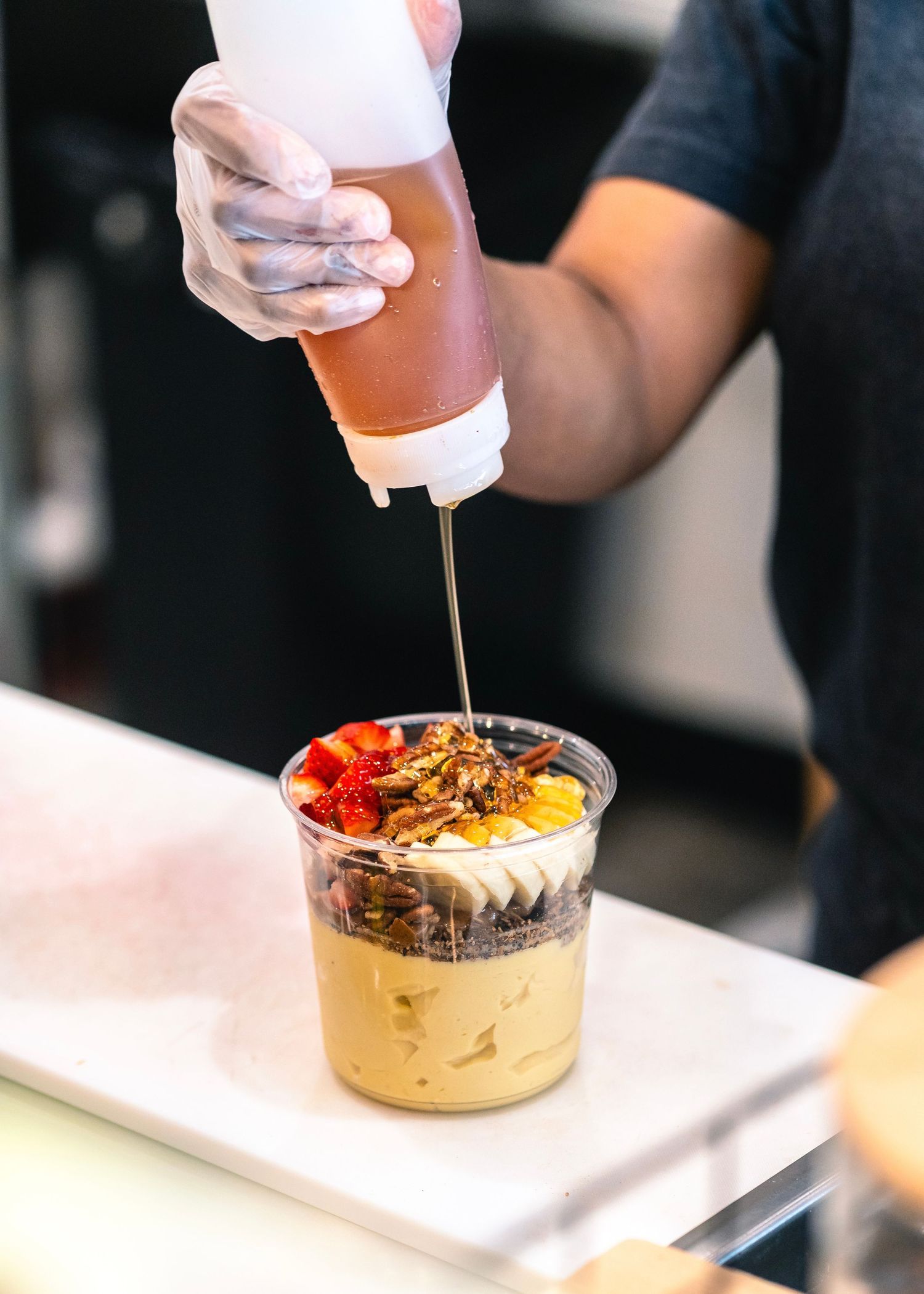 Close-up of a smoothie bowl being garnished with drizzled honey in Ferguson, Missouri.