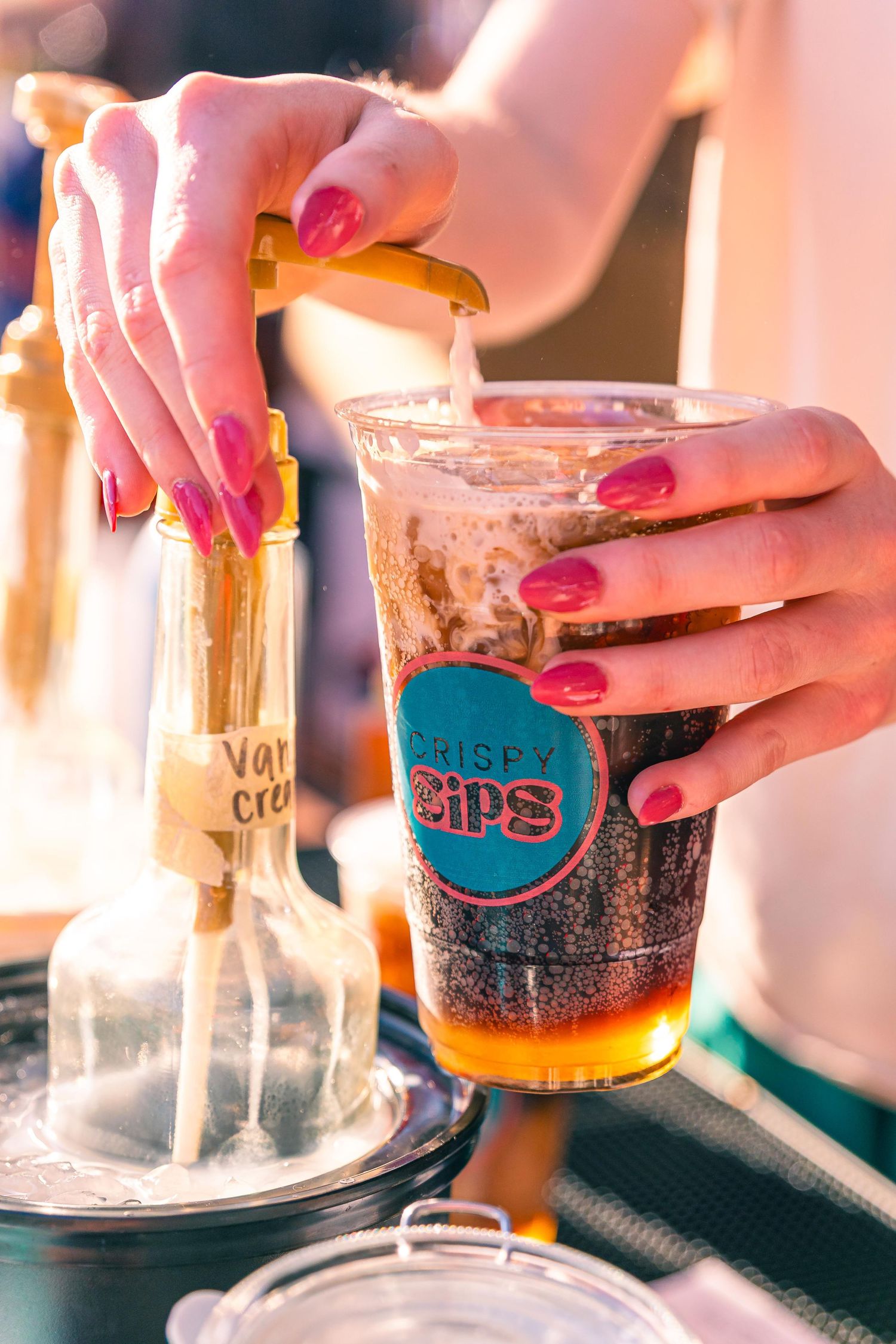 Hands pouring drinks into glasses with Crispy Sips branding. A dirty soda shop in St. Louis.