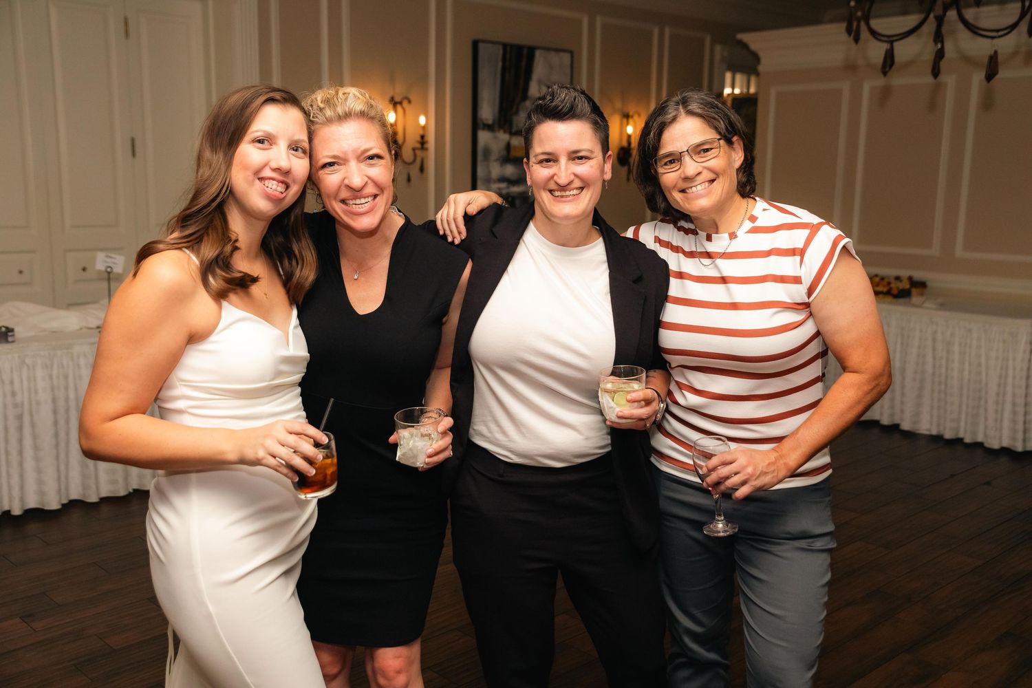 A group celebrates a wedding together in a reception hall with white walls and elegant decor.