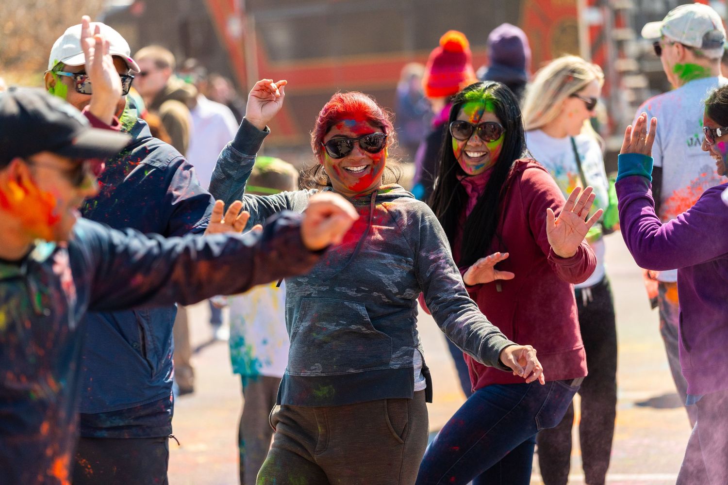 A group of people dancing and celebrating at an outdoor festival/event near St. Louis with colorful clothing.