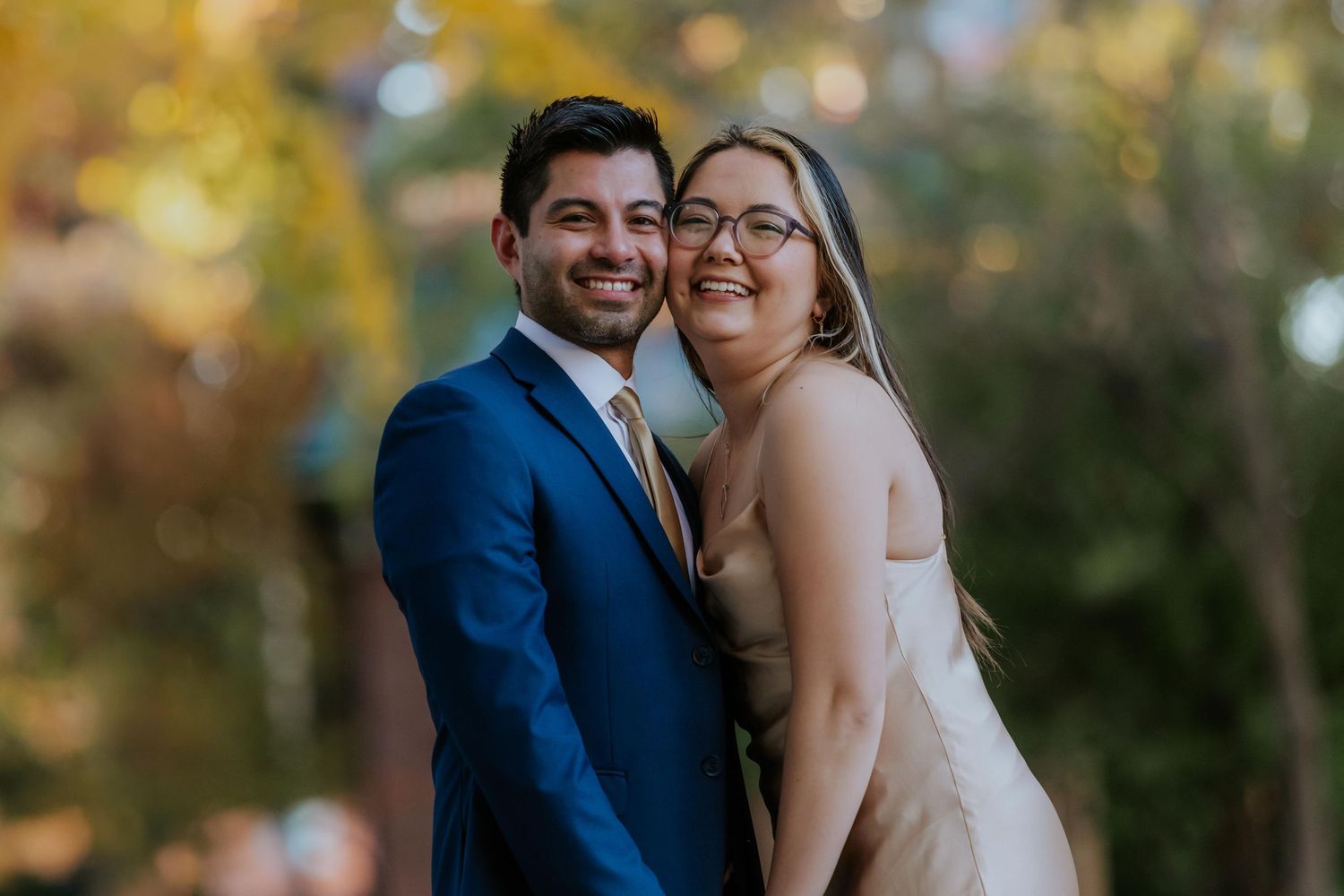 A couple shares a joyful moment together during their engagement photoshoot with leaves in the background at Lafayette Park in St Louis.