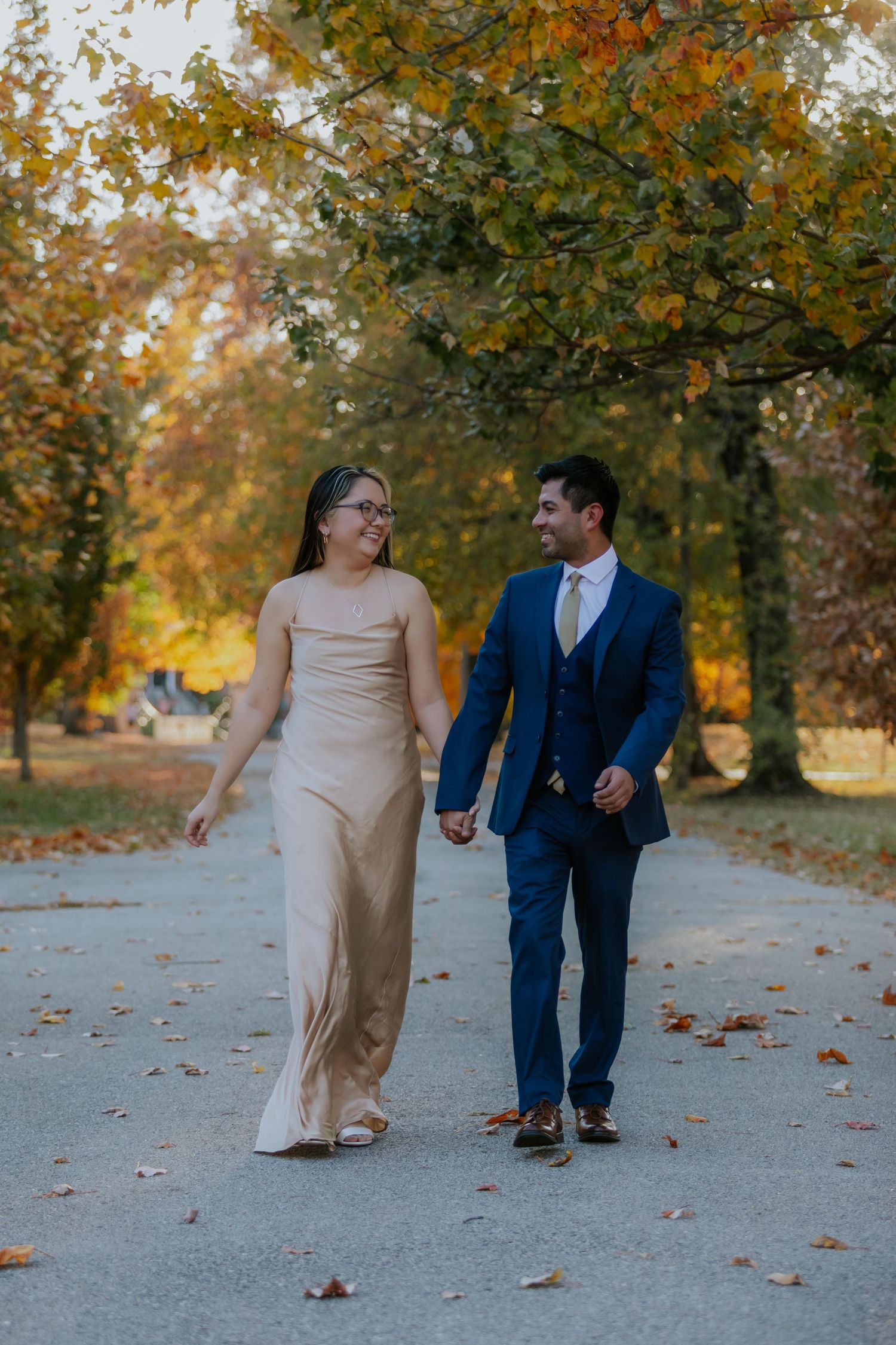 Couple walking together on path surrounded by autumn trees at Lafayette Park in St. Louis.