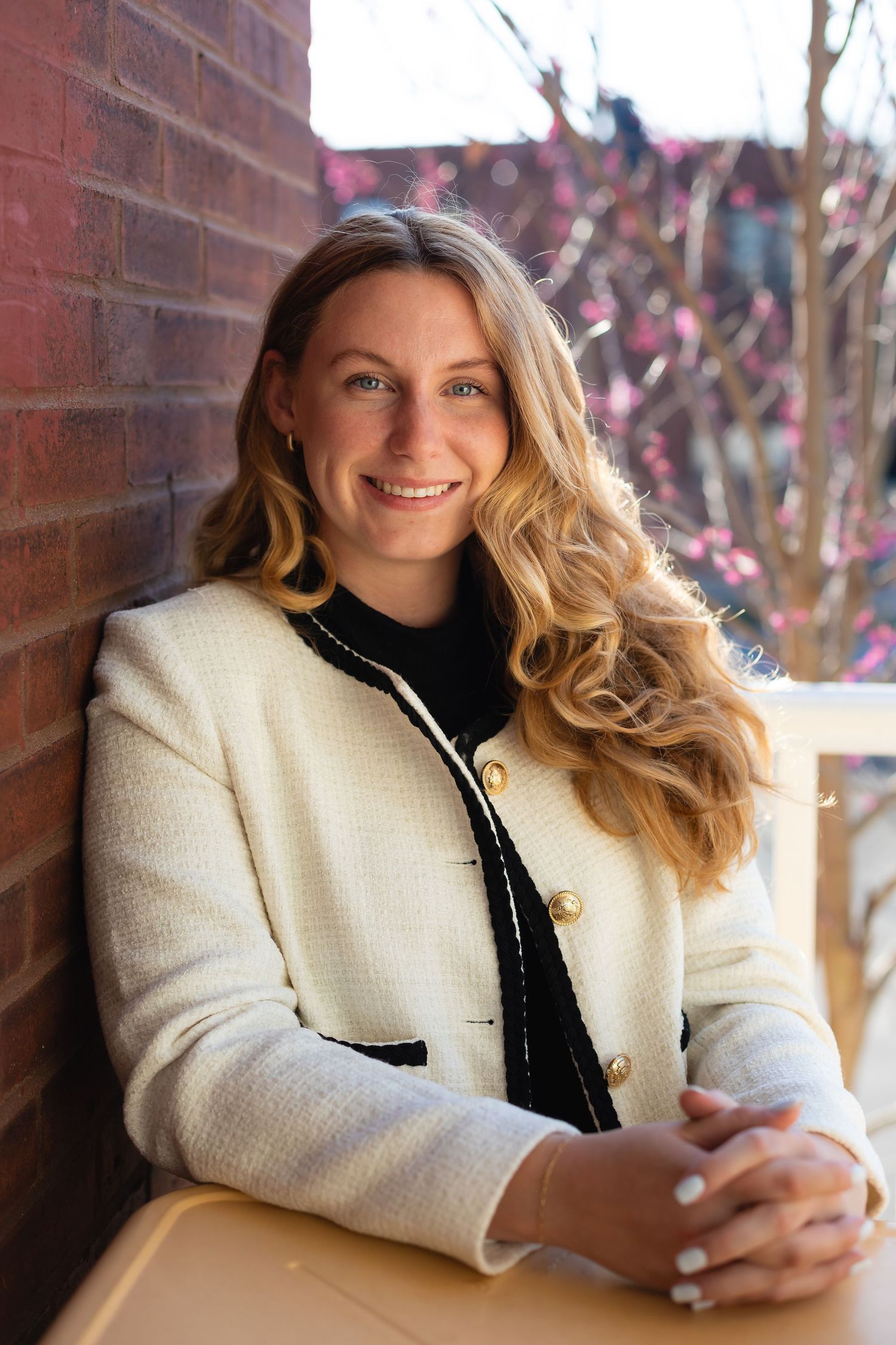 Professional portrait of person in cream colored jacket against brick wall background in St. Louis.