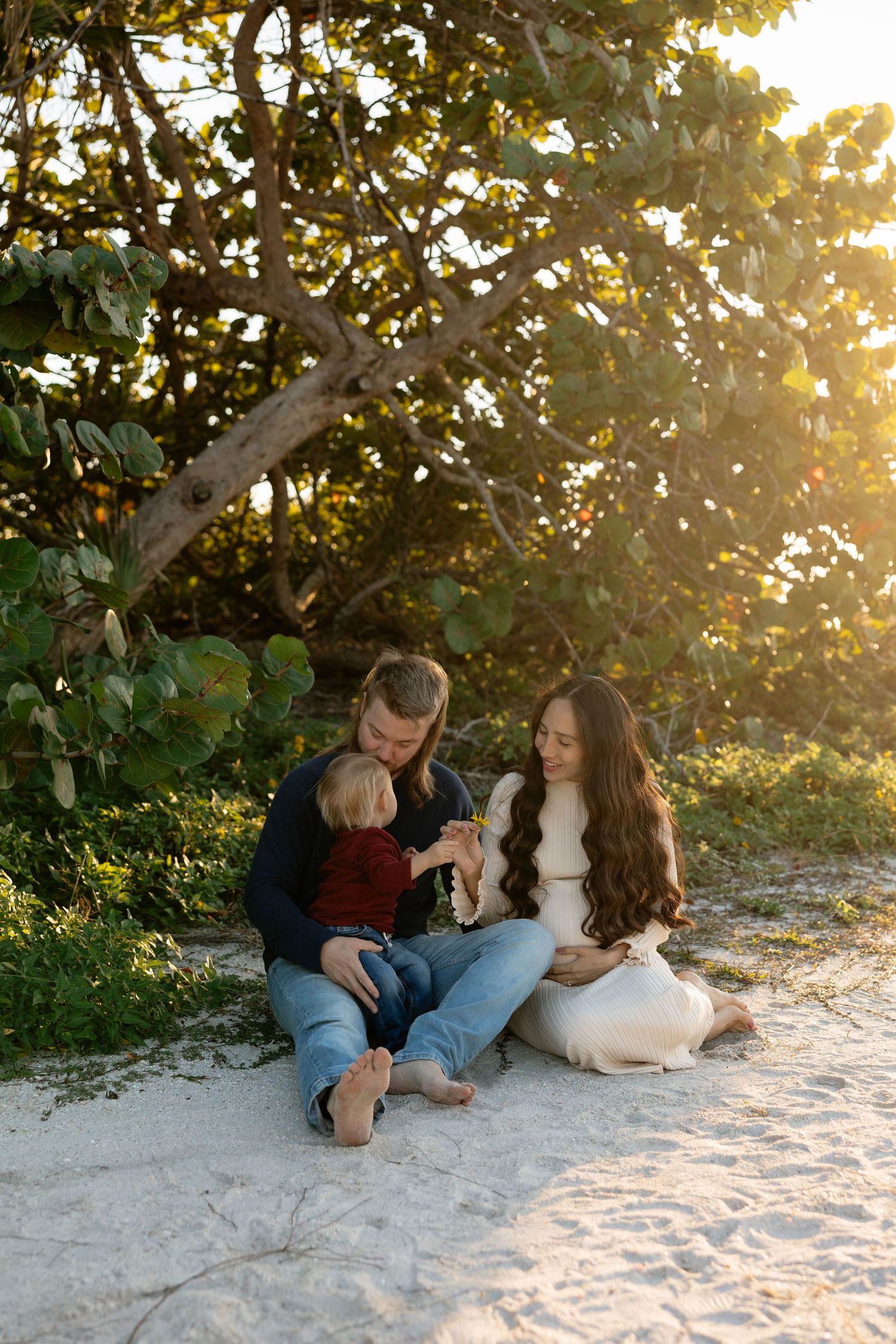 Family relaxing together on sandy beach at golden sunset.