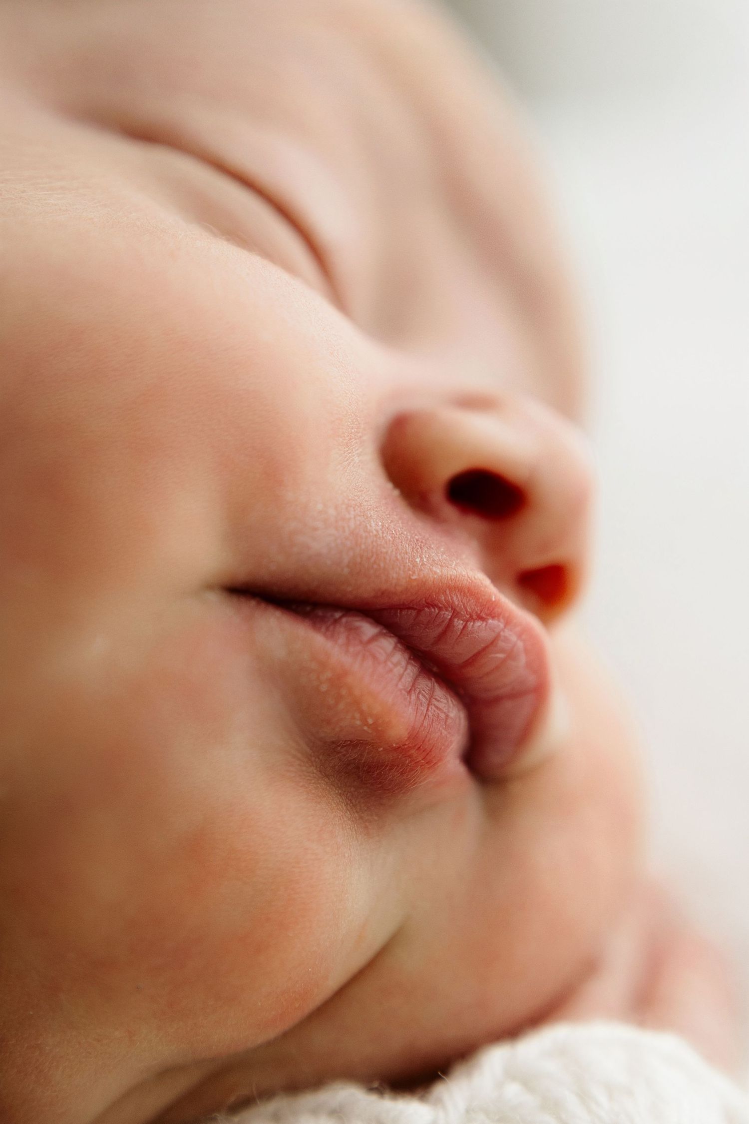 Close-up macro photo of a sleeping newborn baby's nose and lips, showing delicate skin details.