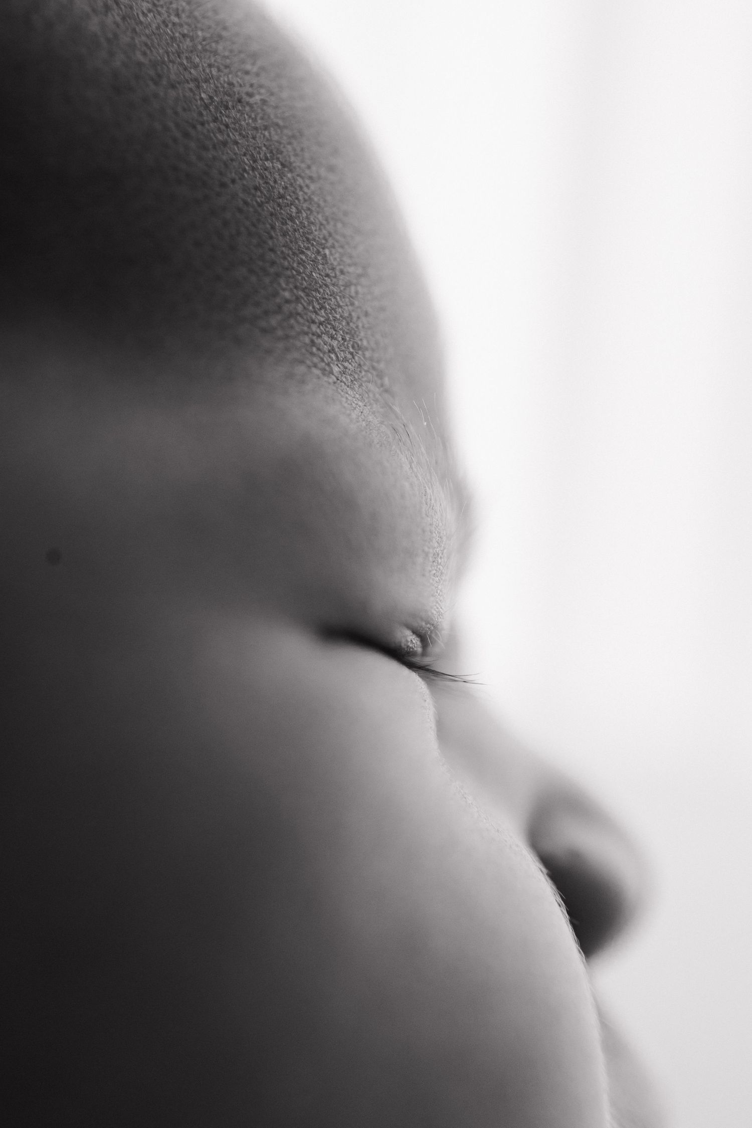 Close-up black and white portrait of a sleeping newborn baby showing delicate facial features.