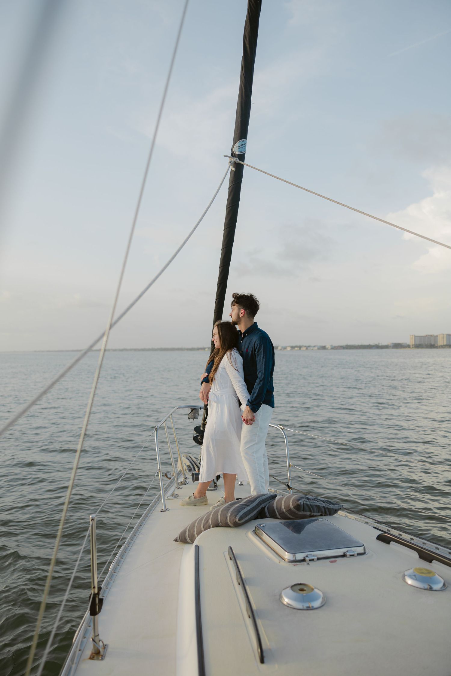 Two people relax on the deck of a sailboat during a peaceful day at sea.