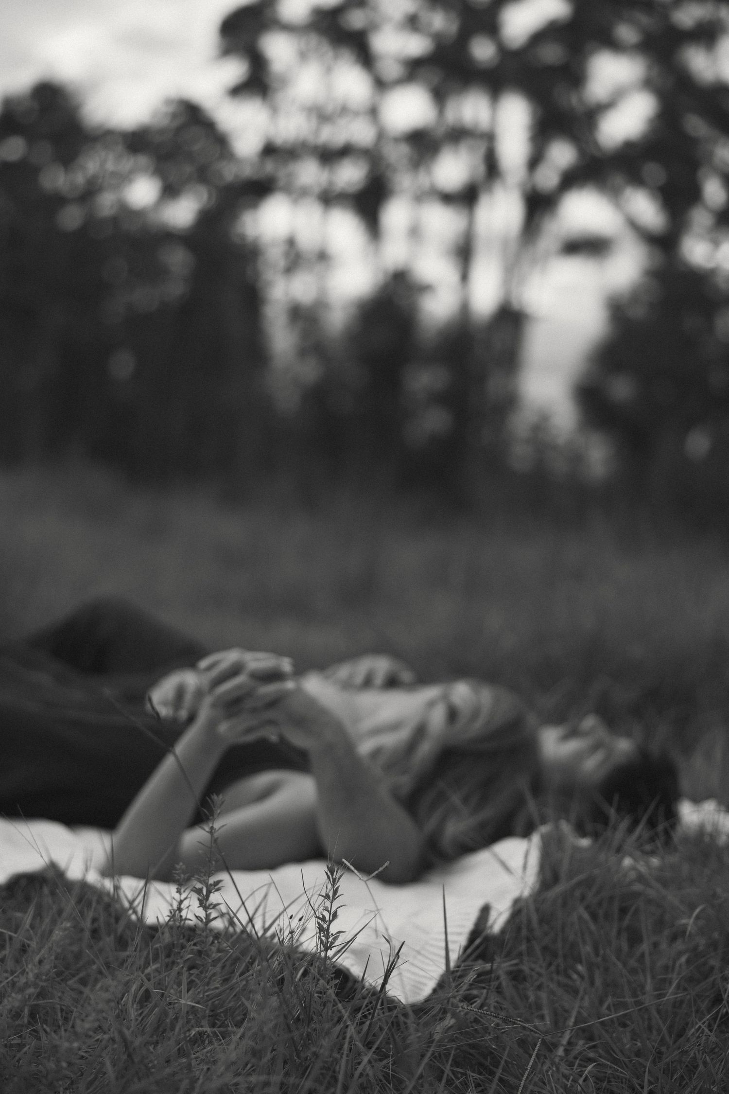 Romantic black and white portrait of couple lying in tall grass.