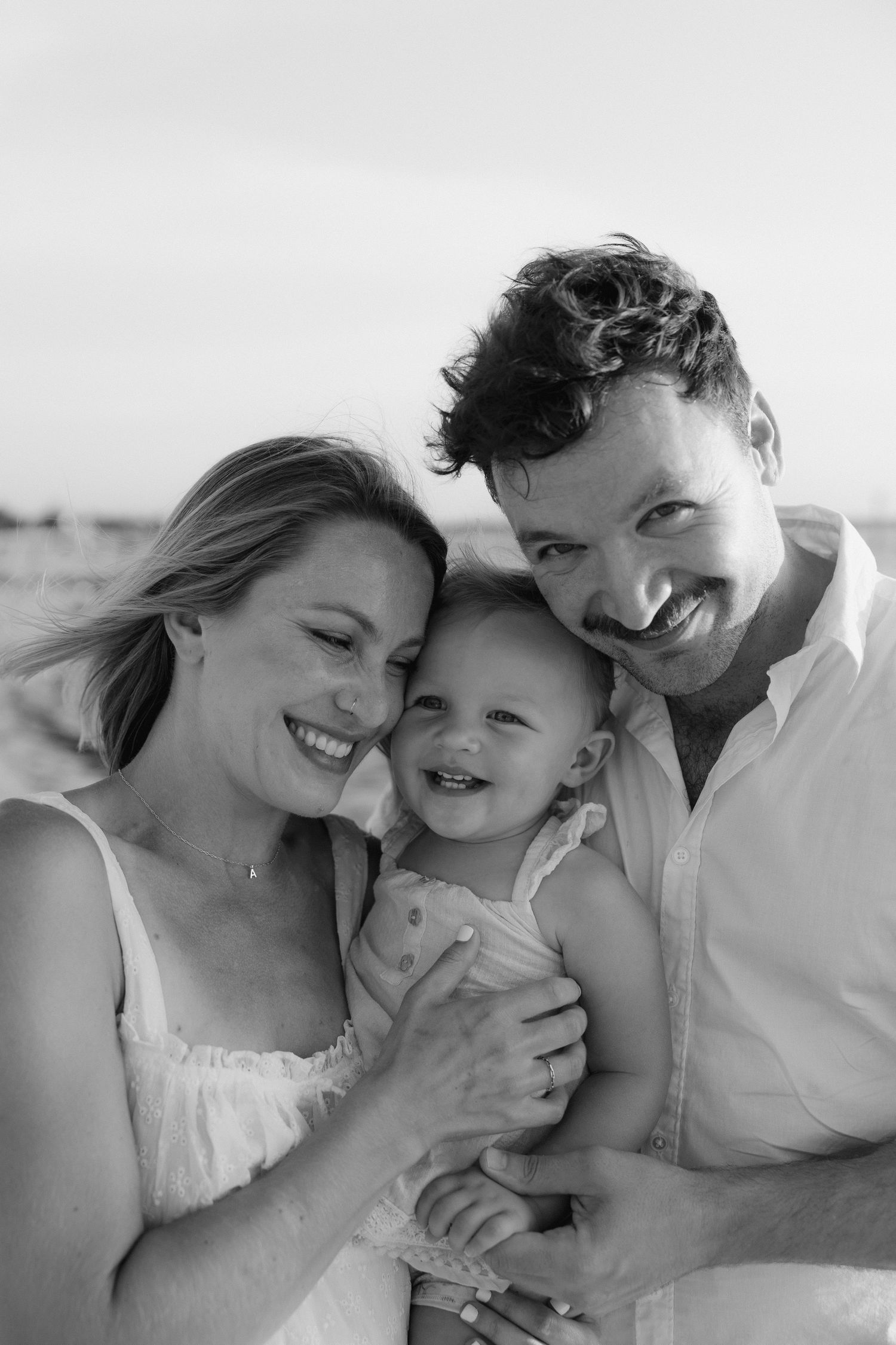 A black and white close-up portrait of a joyful family moment outdoors.