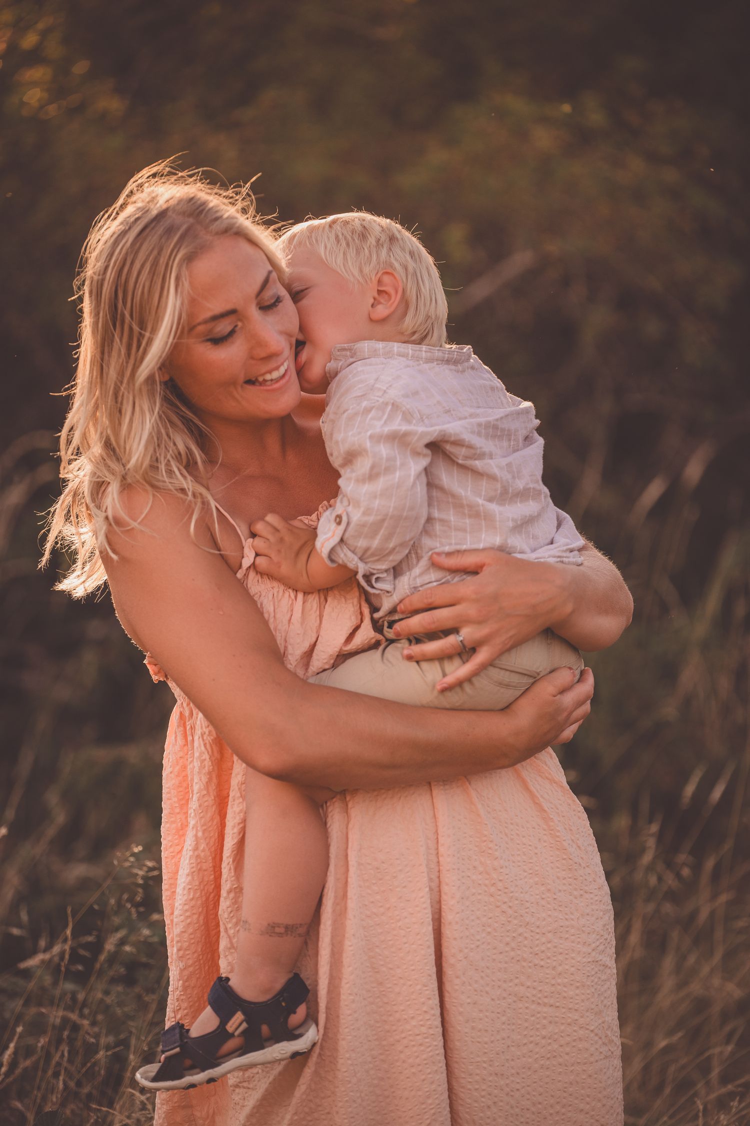 A tender moment between parent and child captured in warm sunset lighting in a natural outdoor setting.