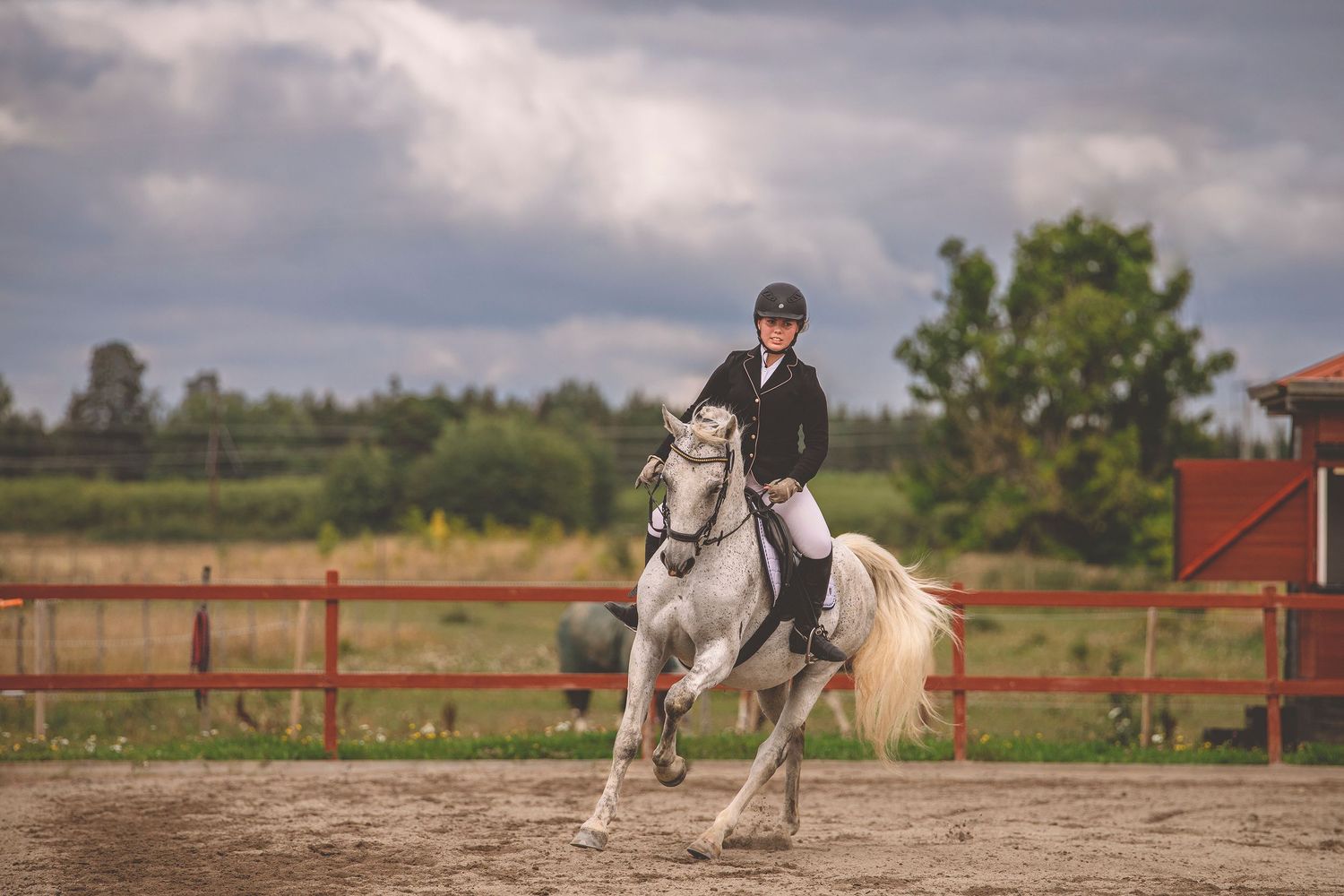 Equestrian event taking place on a cloudy day with horses and riders in an outdoor arena.