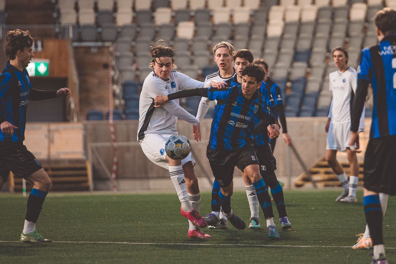 Soccer players competing intensely for the ball during a match on artificial turf.
