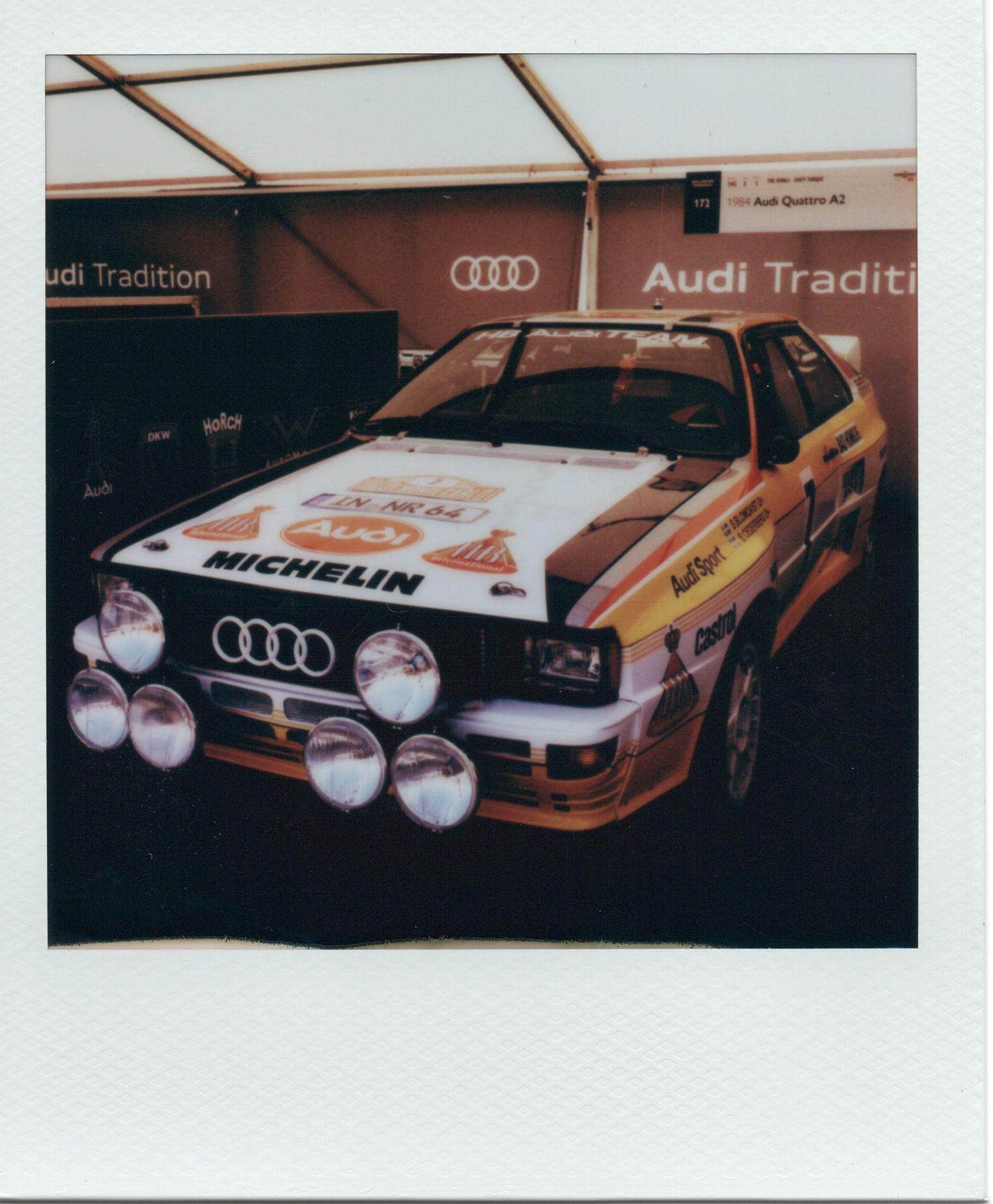 Audi Tradition rally car with Michelin sponsorship displayed at an Audi Tradition exhibit, featuring classic racing livery.