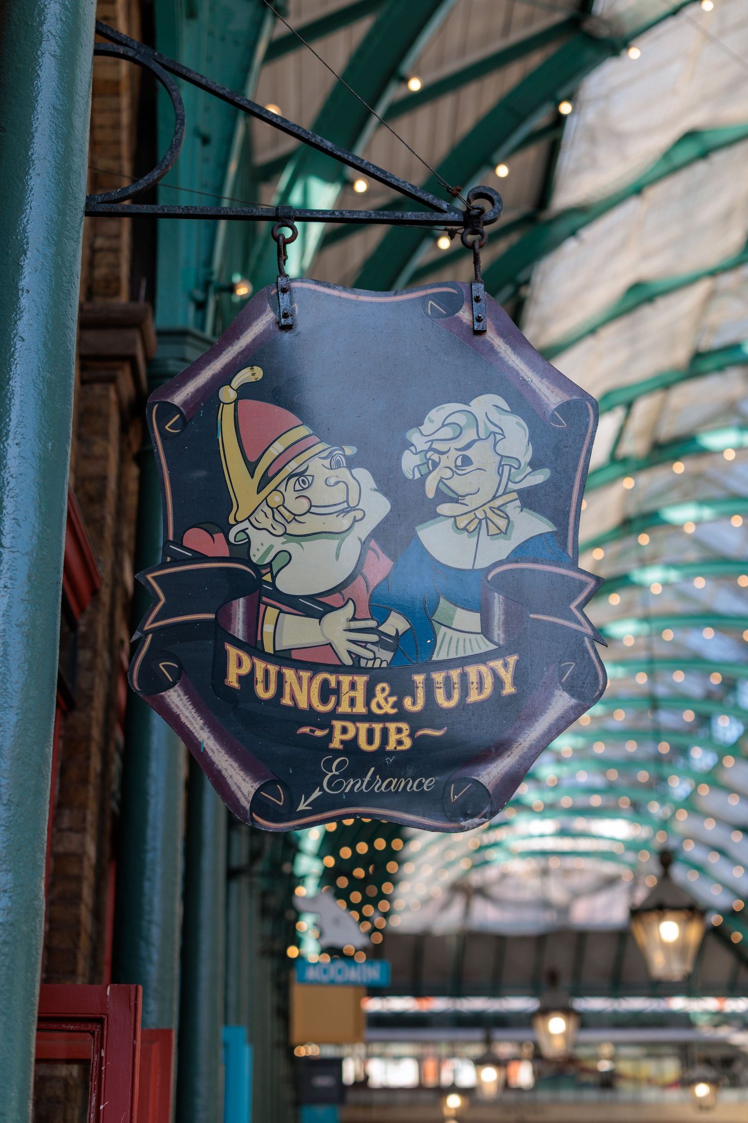 Punch & Judy Pub entrance sign hanging in Covent Garden Market, London, featuring classic puppet characters.