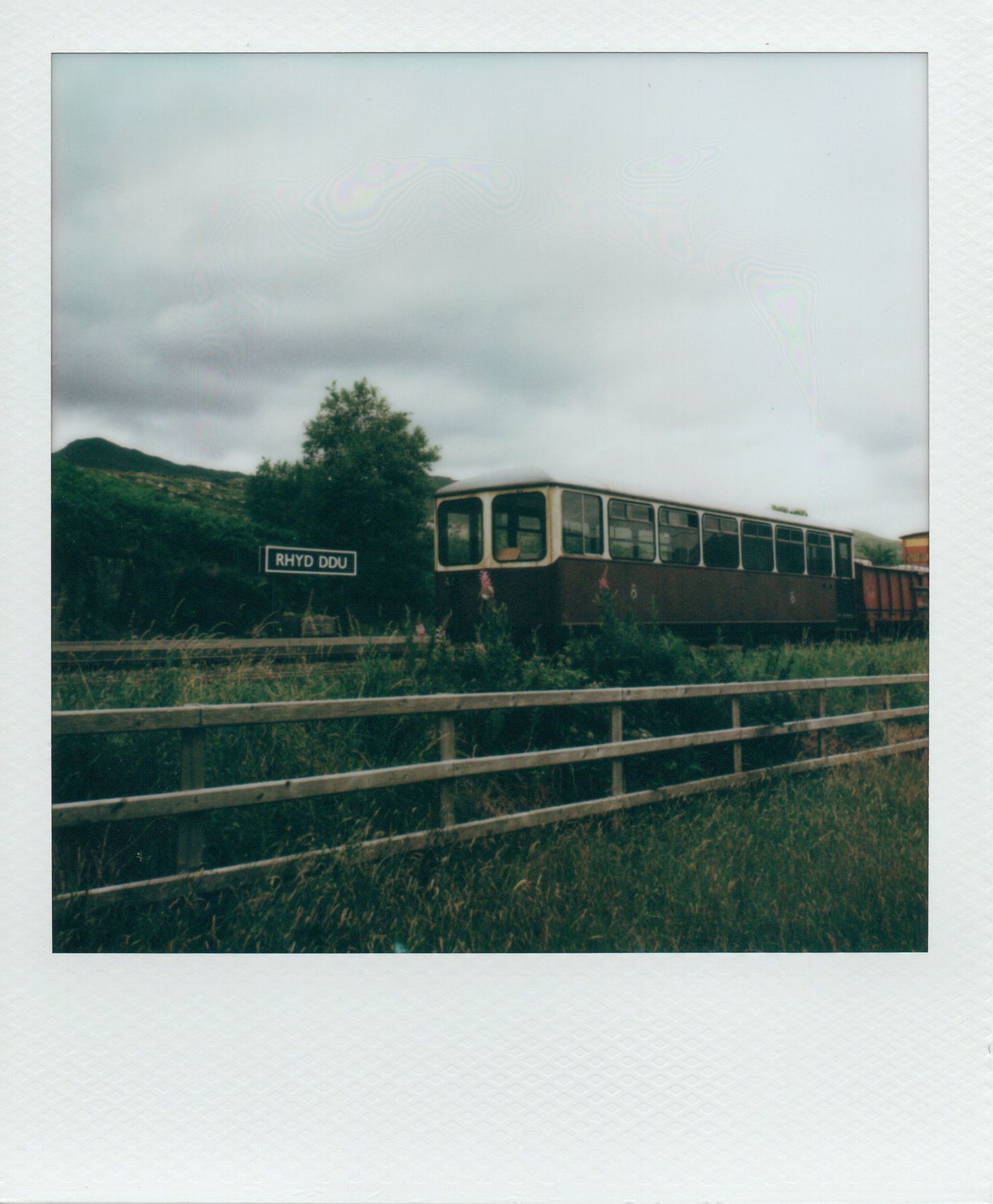 Vintage train carriage parked at Rhyd Ddu station in Wales on an overcast day.