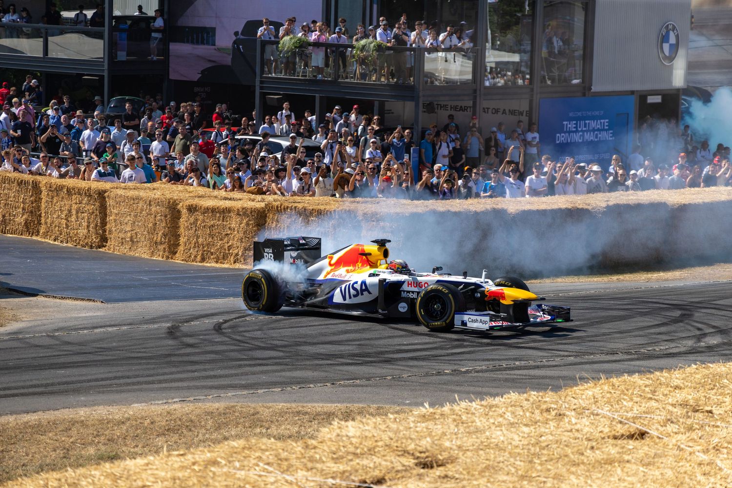 Red Bull Formula 1 car performing smoky donuts at Goodwood Festival of Speed with crowds watching.