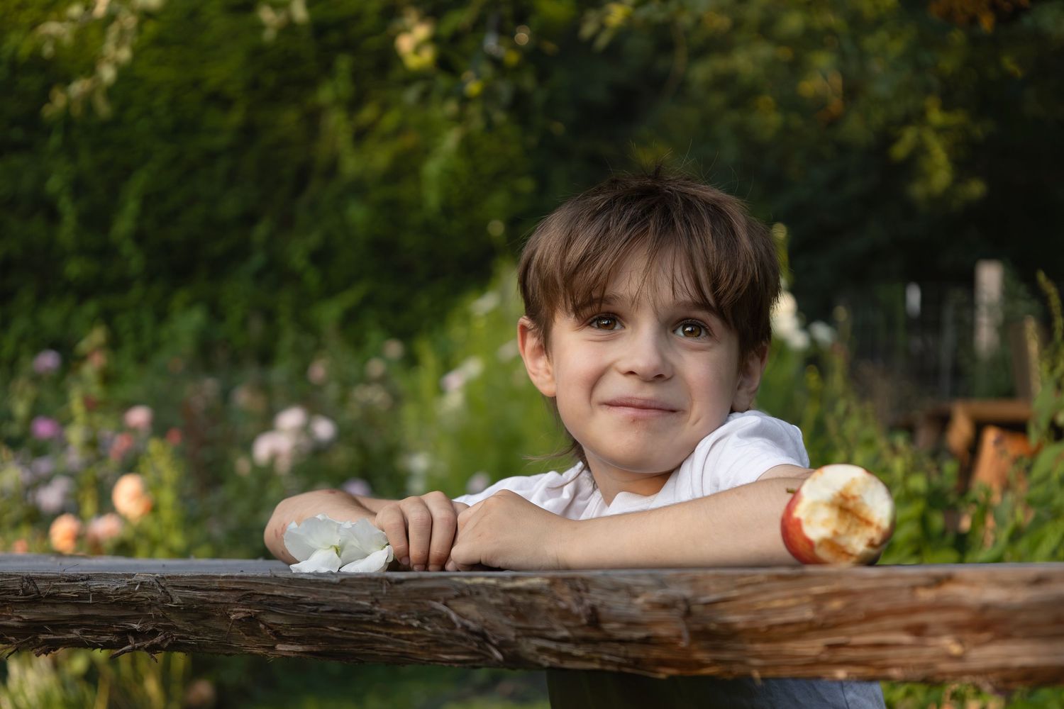 A young boy stands in a flower field while looking lovingly at his mom off camera.