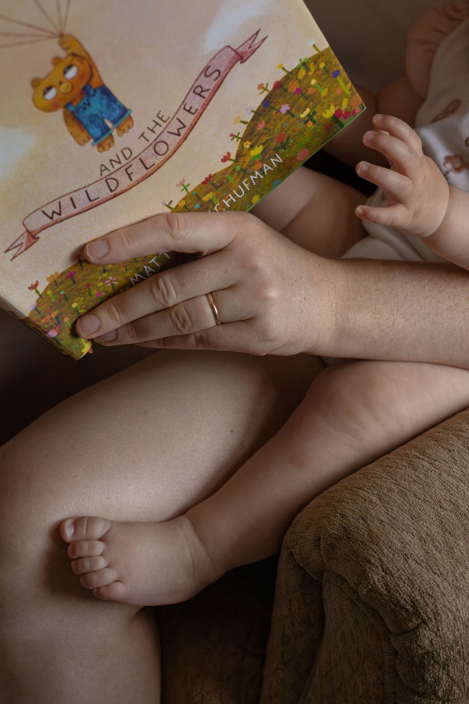 A mom cuddles with her baby in a chair in the nursery while reading her a story.
