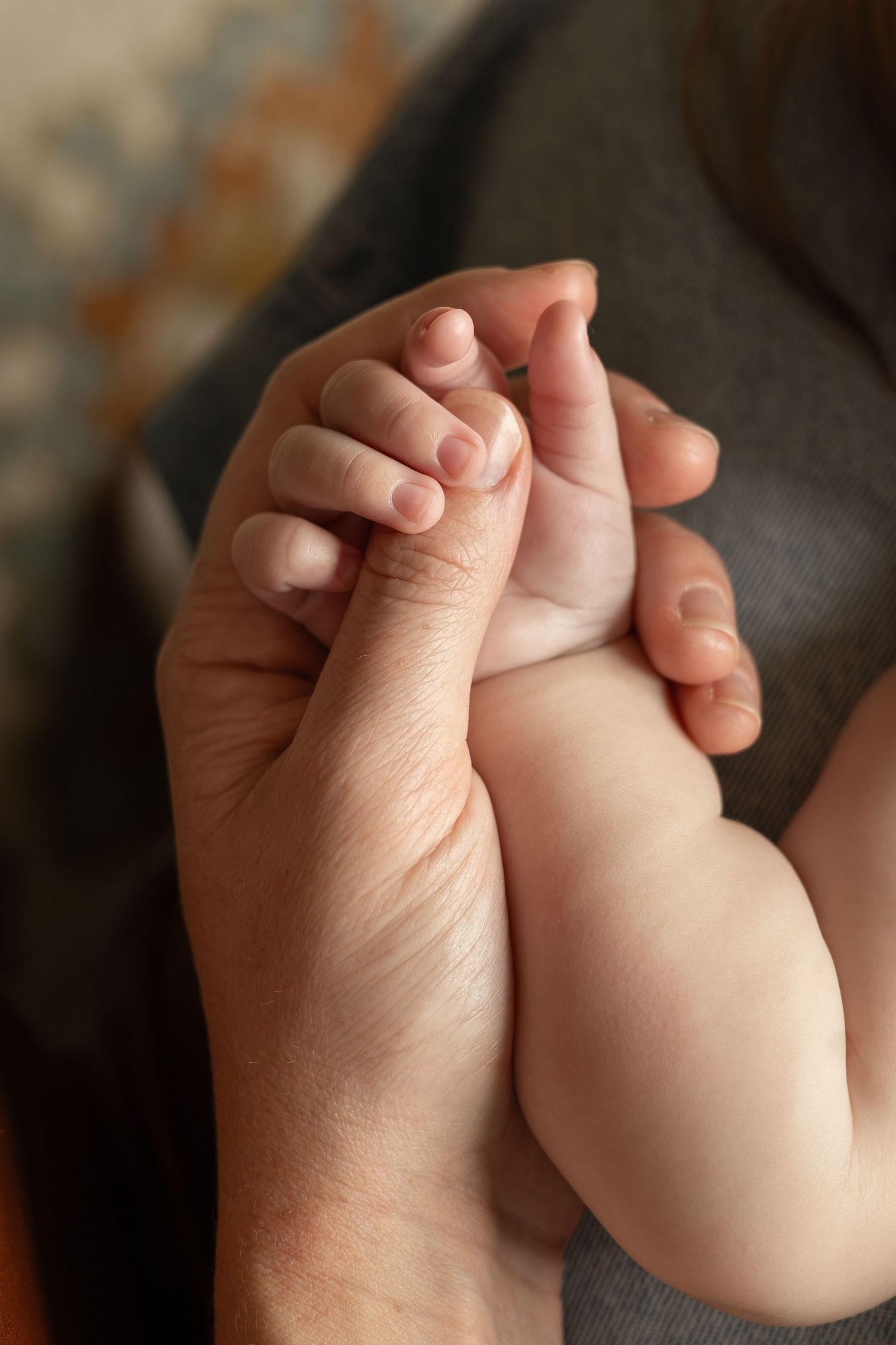 A closeup of a mom holding onto her baby's hand.