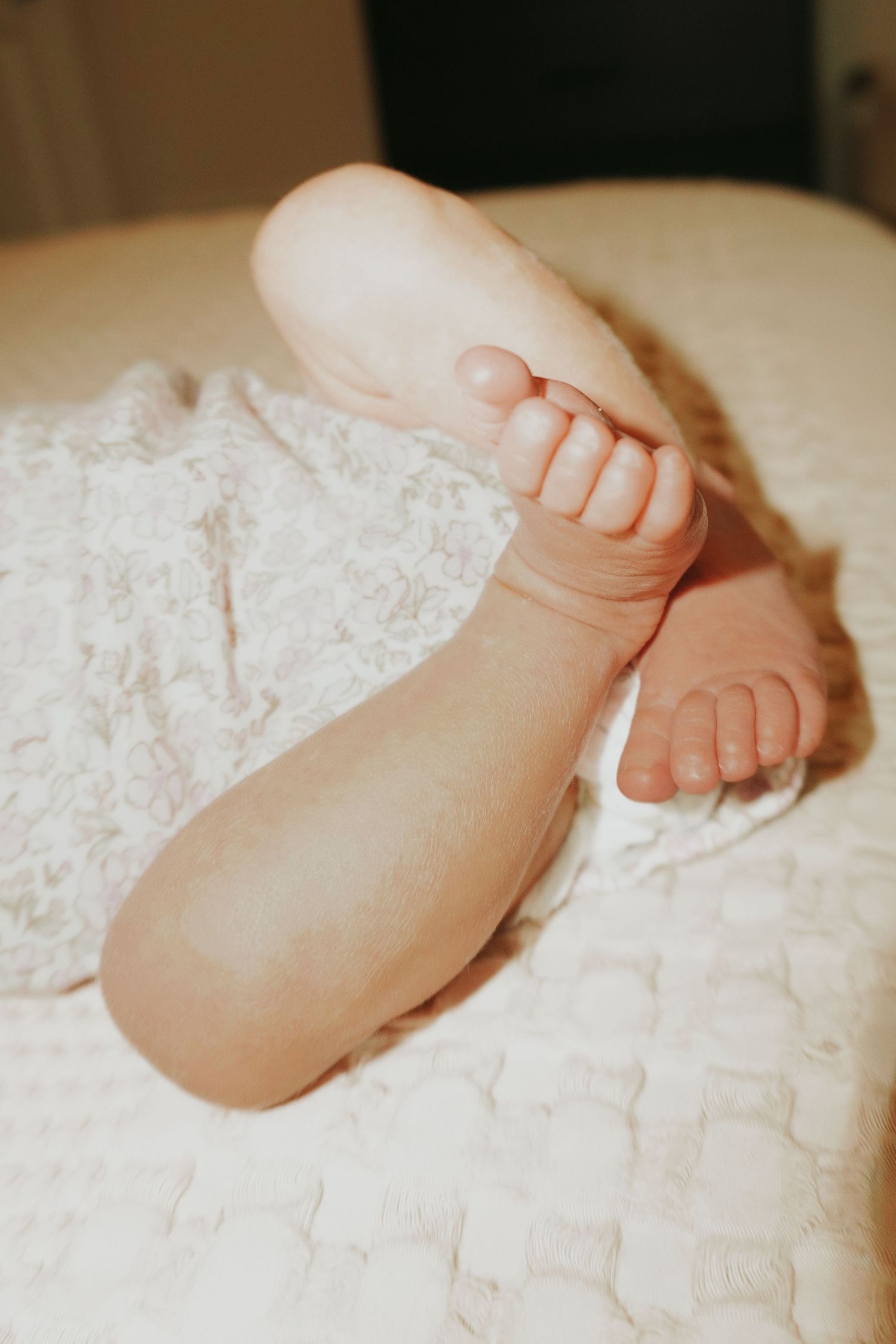 Close-up of tiny newborn baby feet resting on a soft white blanket.