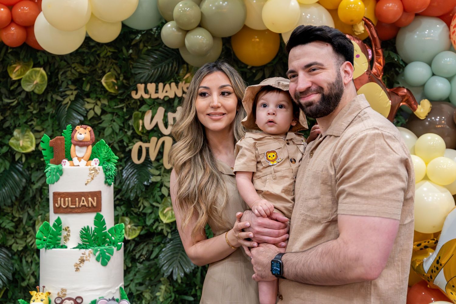 family posing in front of jungle themed birthday cake and backdrop