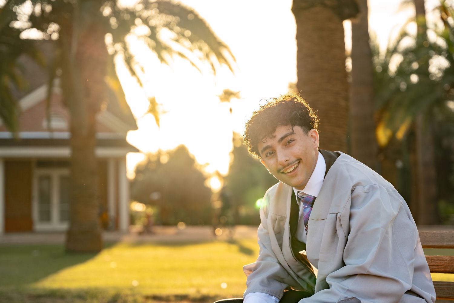 boy posing with a large smile in his graduation regalia