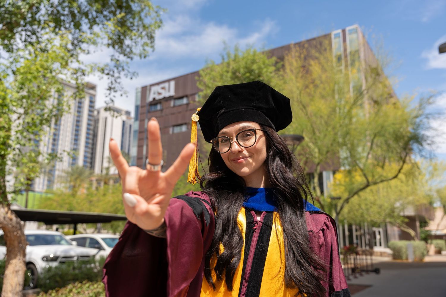 girl graduates and does the forks up hand gesture in her Ph.D regalia