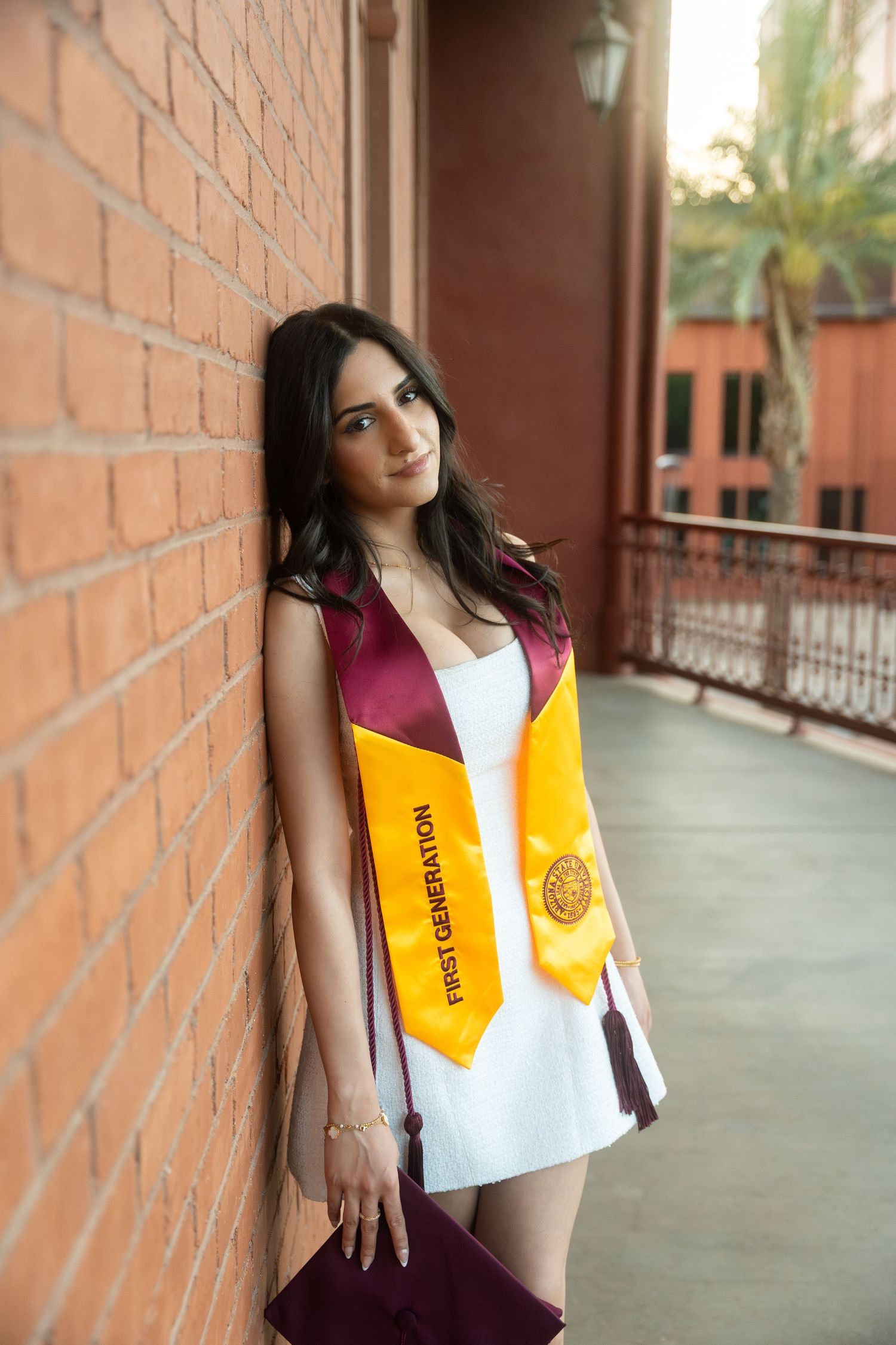 woman leaning on a brick wall in her regalia