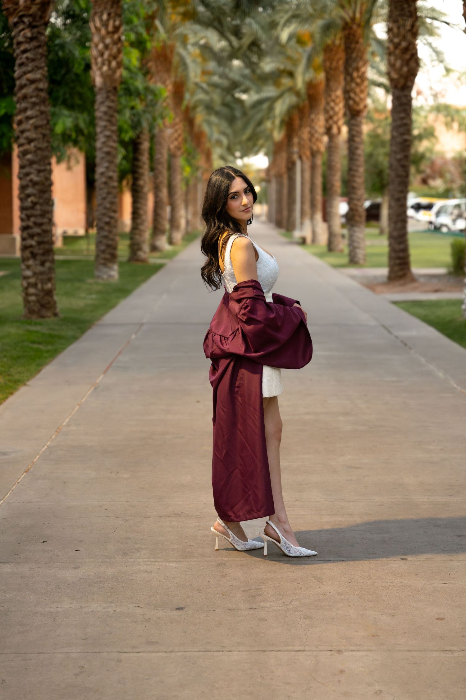 woman posing in her regalia with palm trees in the background