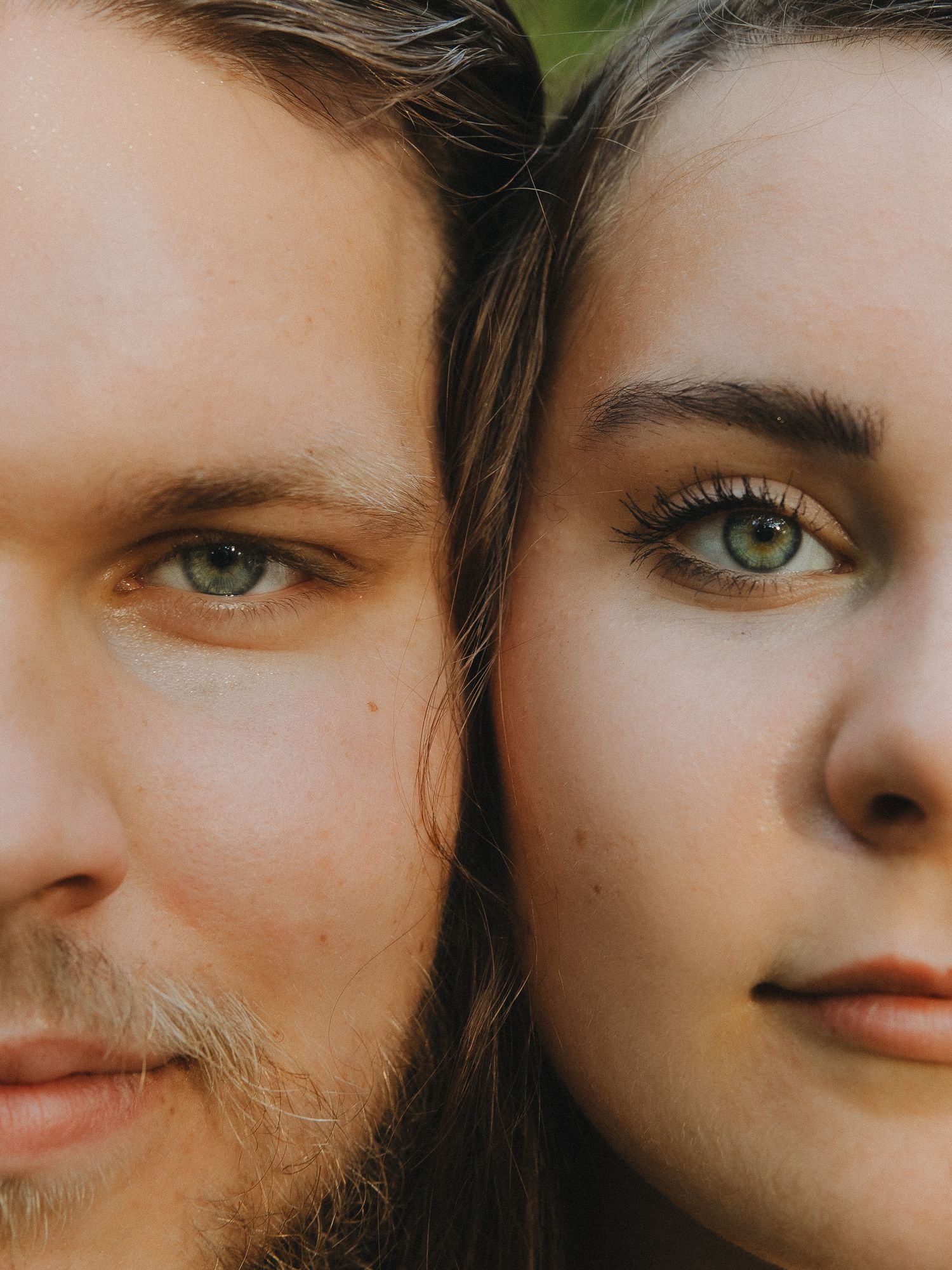 Close-up portrait of a couple with striking green eyes facing the camera side by side.