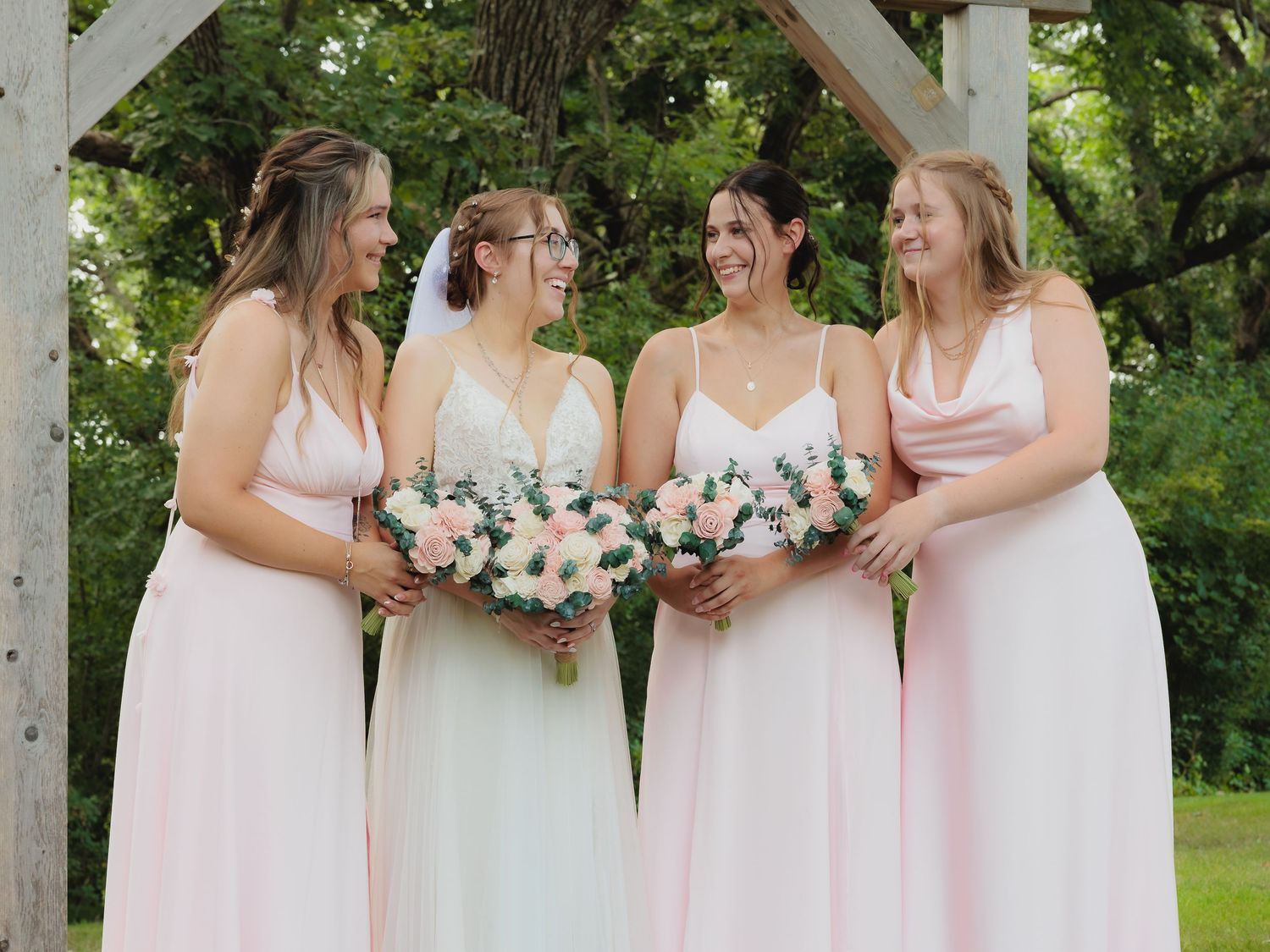 Bride in white gown with three bridesmaids in pink dresses holding bouquets.