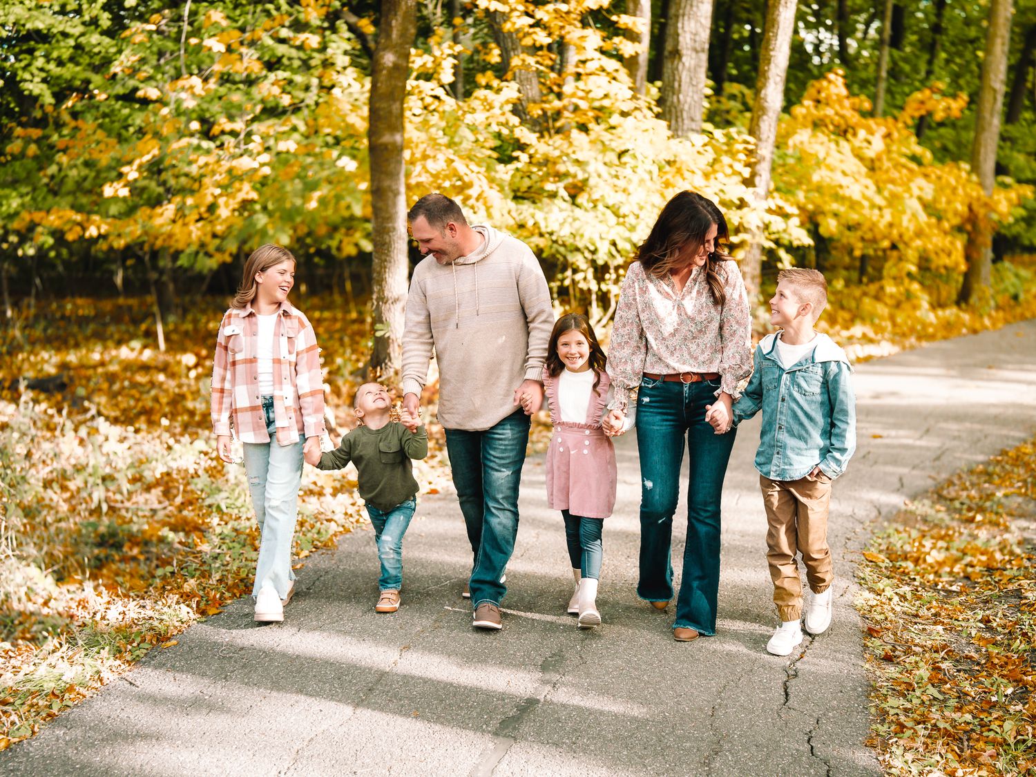 Family of six walking together on a path surrounded by golden autumn foliage.