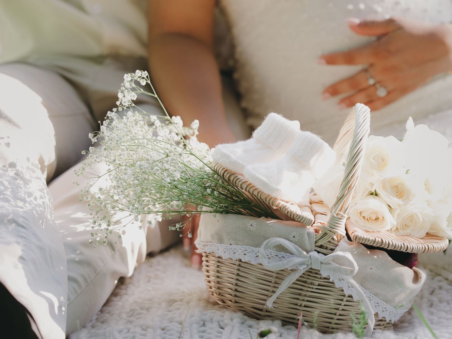 Elegant wedding basket with baby's breath flowers, white roses, and ribbon on a lace surface.