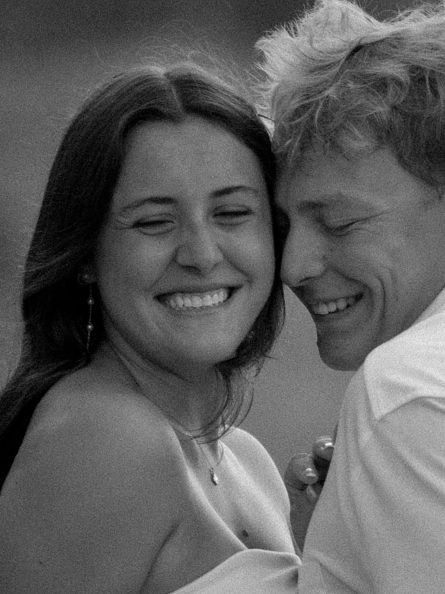 Black and white photo of a smiling couple embracing closely, sharing a joyful and intimate moment together.