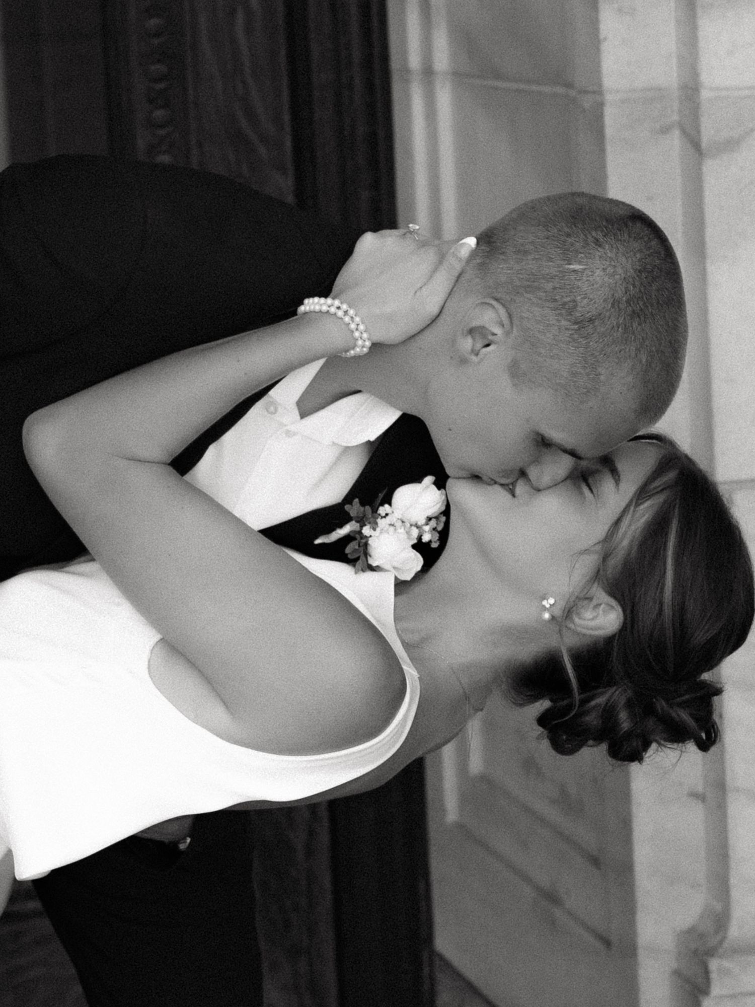 Bride and groom sharing passionate kiss in black and white wedding photo.