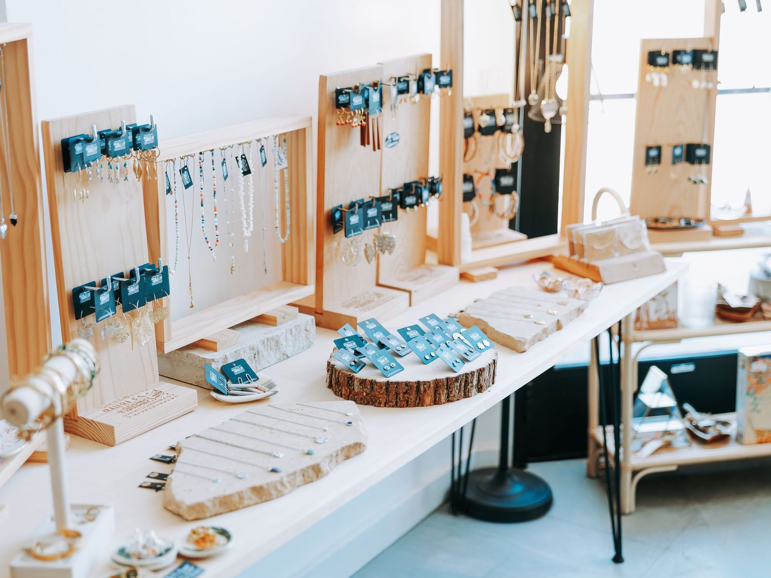 Boutique jewelry display with turquoise and gold pieces on wooden stands and trays.